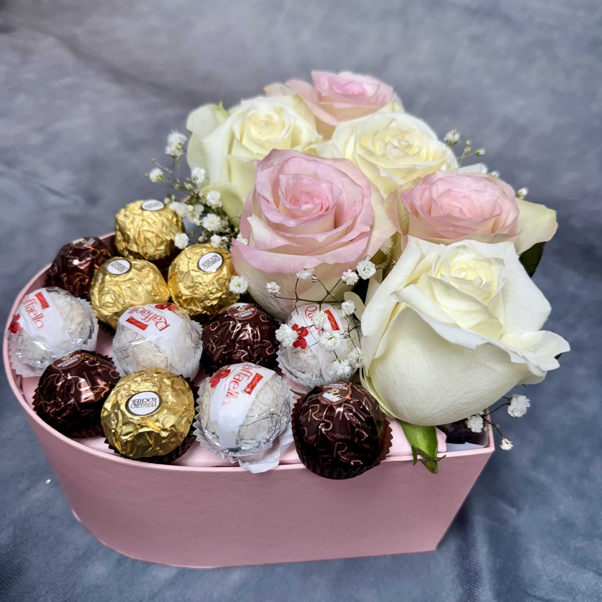 Pink and white roses in a pink box with assorted chocolates
