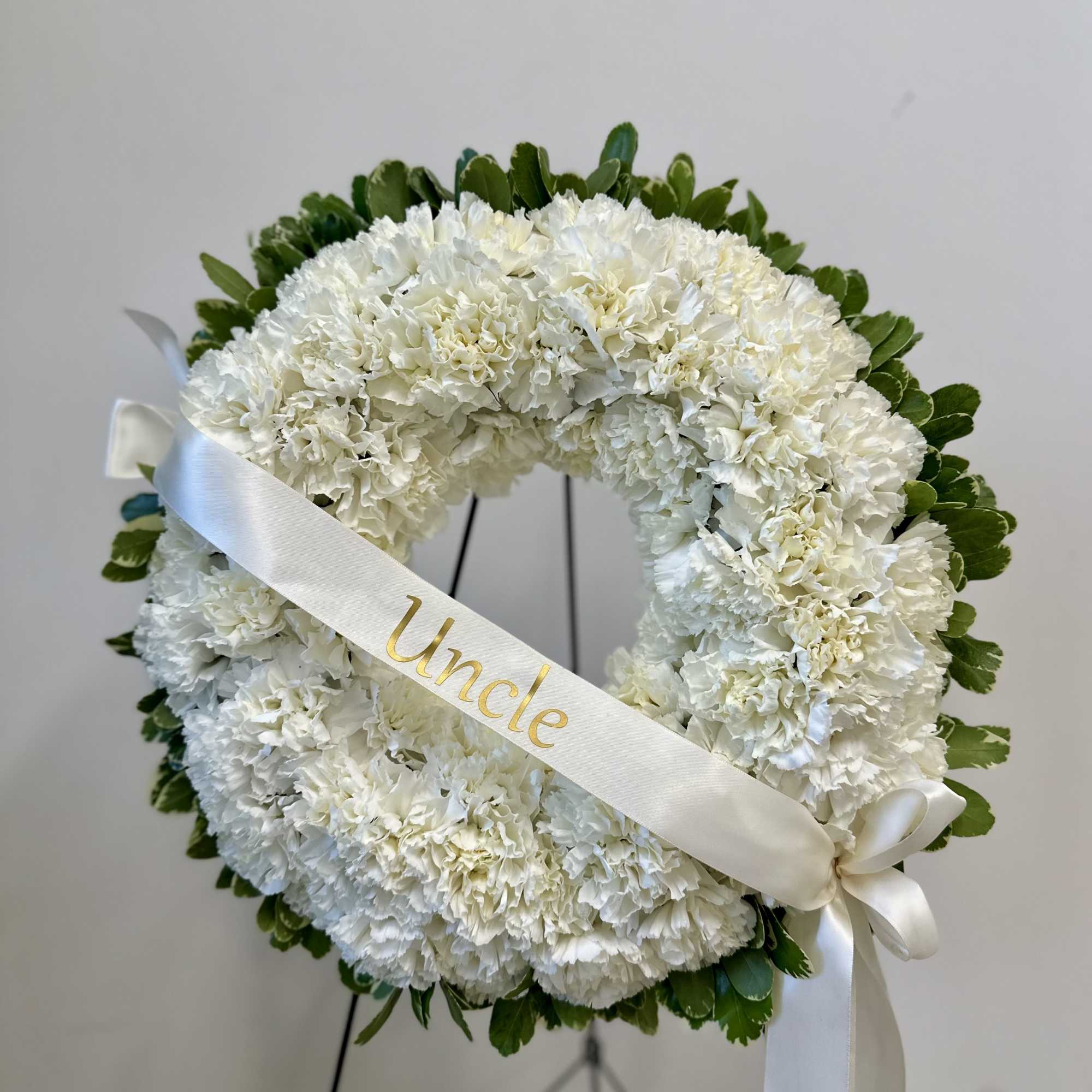 White floral wreath with a ribbon reading Uncle
