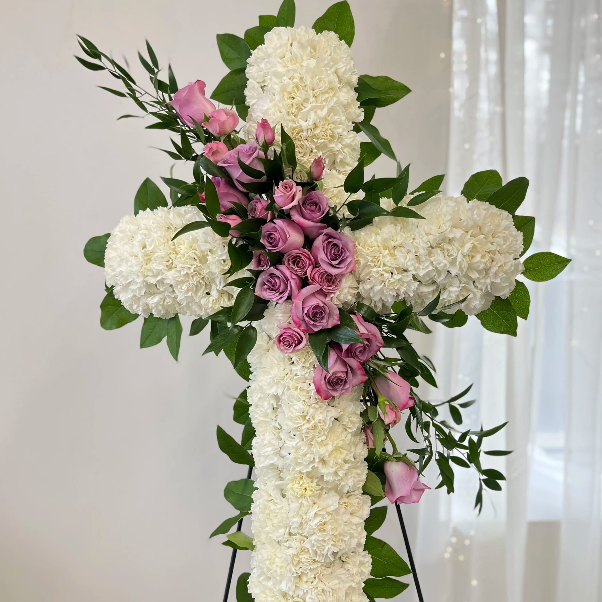 White floral cross with pink roses and greenery
