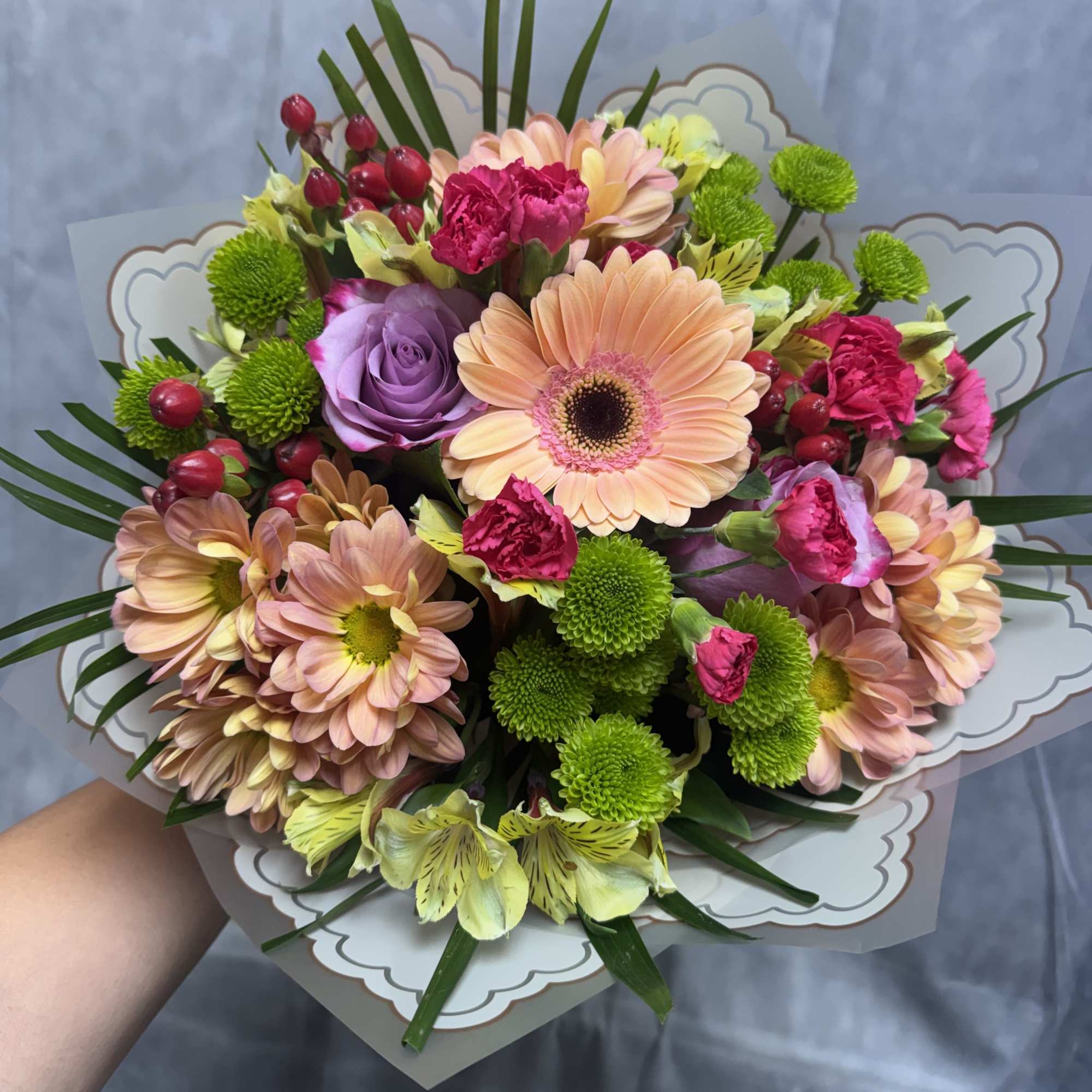 A charming blend of peach, lavender, pink, and green blooms arranged into