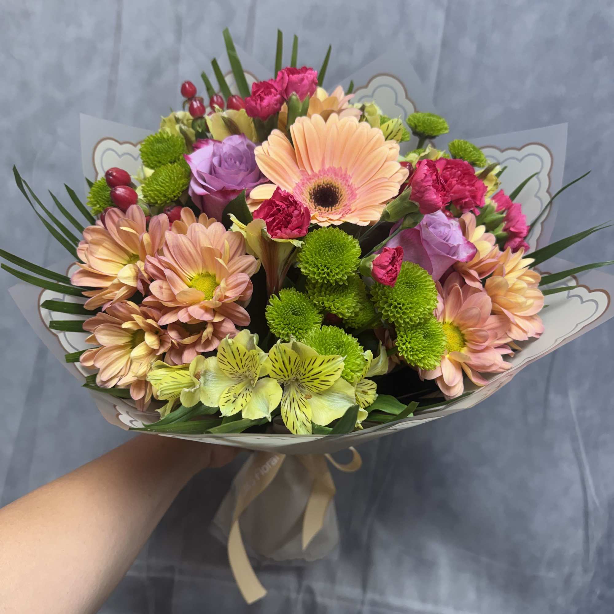 A charming blend of peach, lavender, pink, and green blooms arranged into