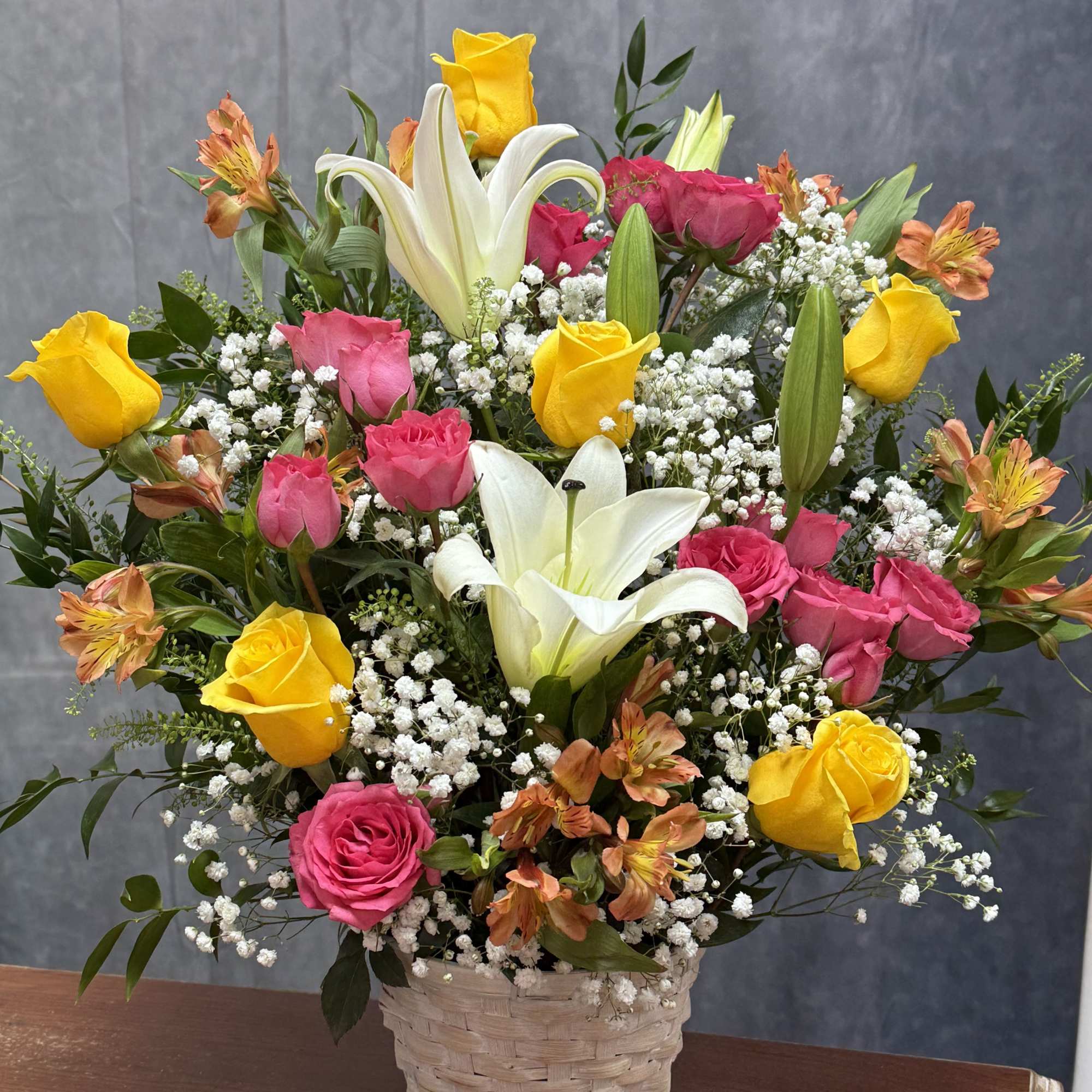 Bright pink, yellow and orange roses and alstroemeria with white lilies and