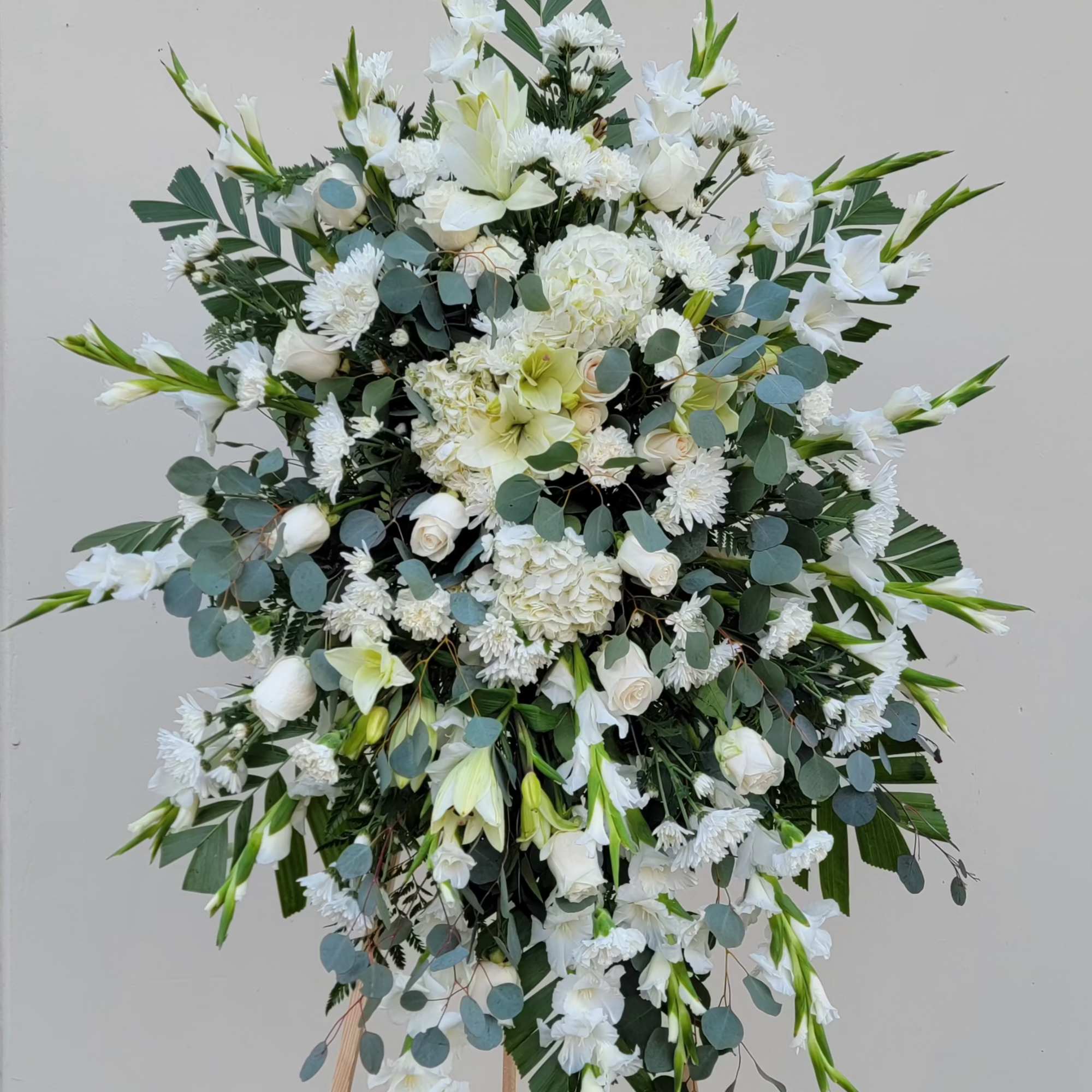 Large white floral standing spray with eucalyptus on an easel