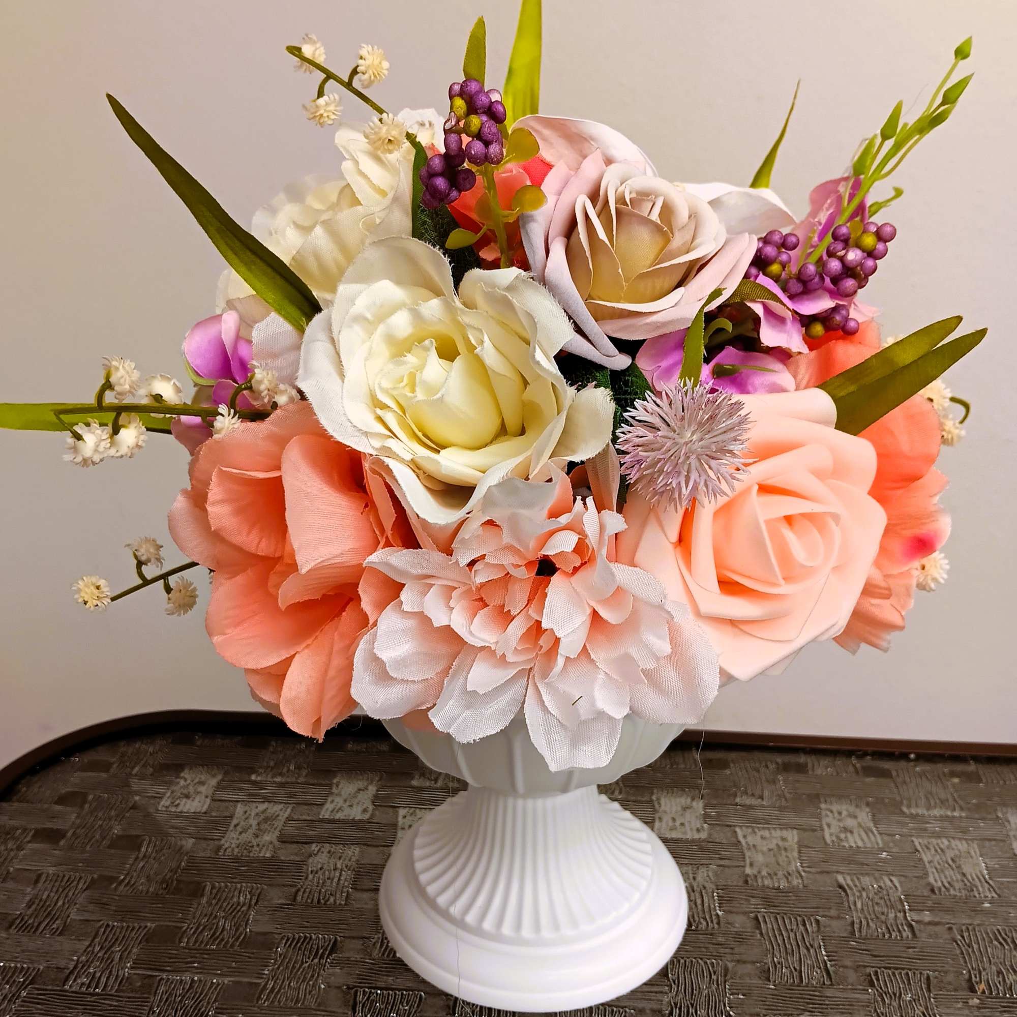 Wedding bouquet of blush, peach, and white flowers in a white pedestal vase