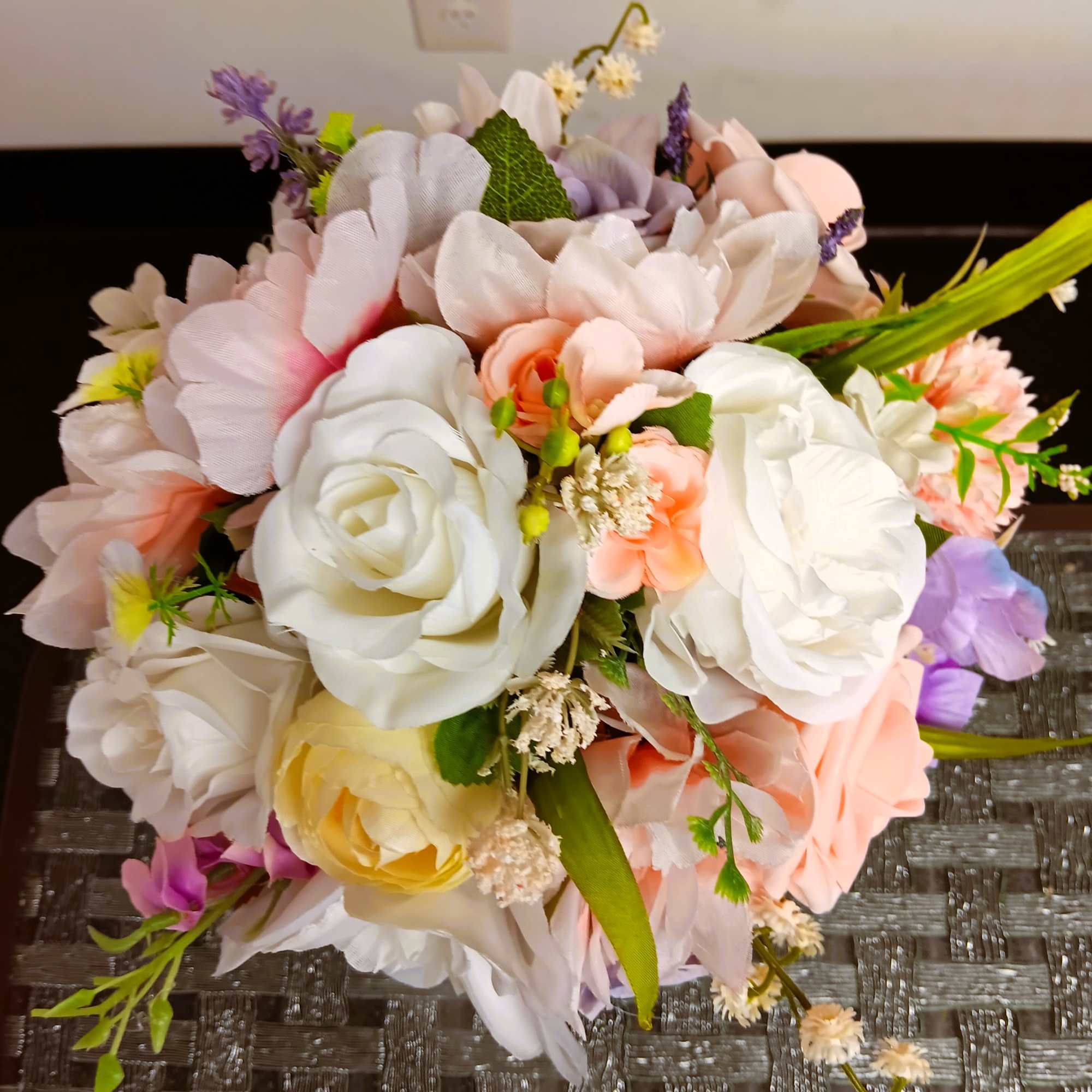 Wedding bouquet of white, blush, and peach flowers with purple accents