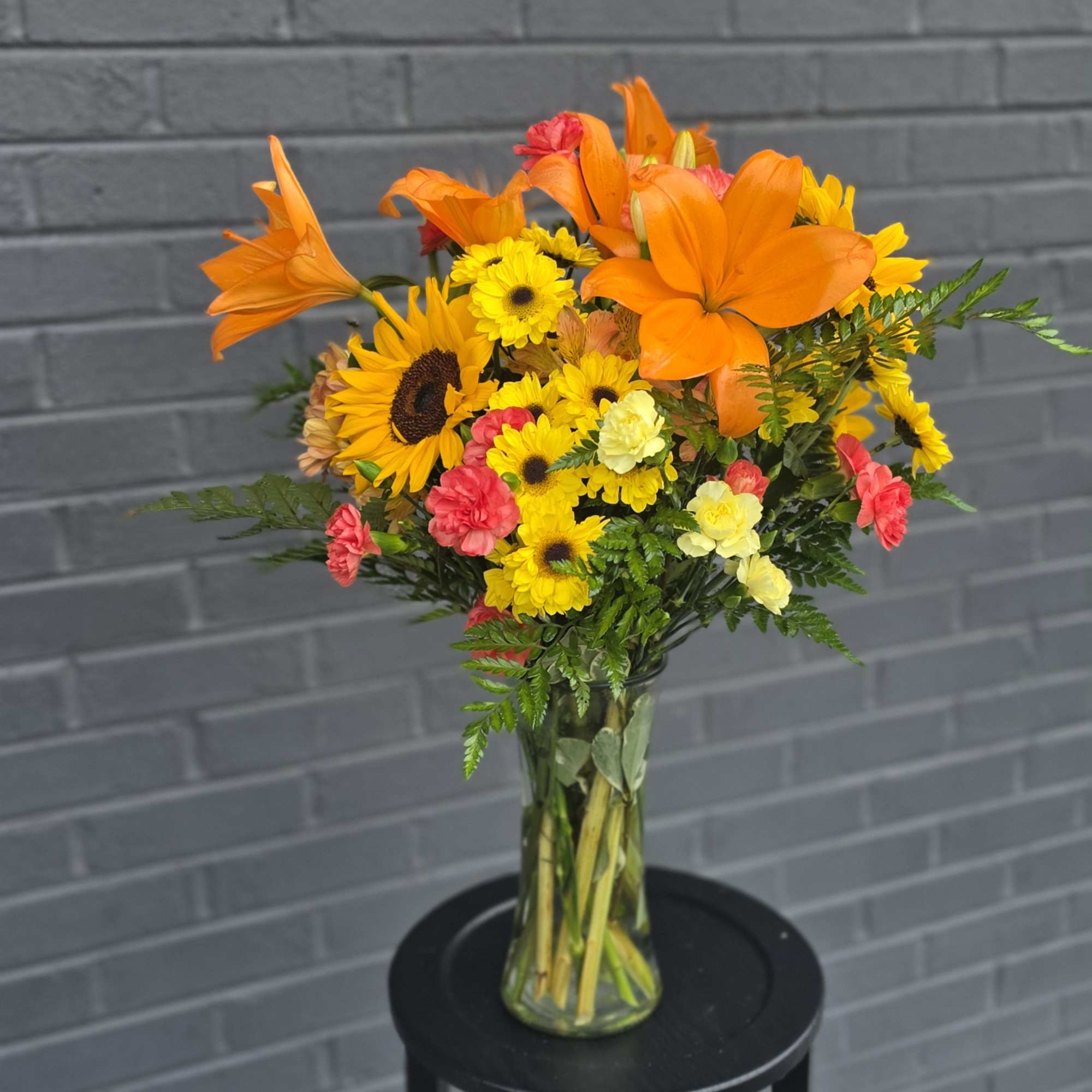 Bright orange lilies take center stage in this cheerful mixed bouquet, making