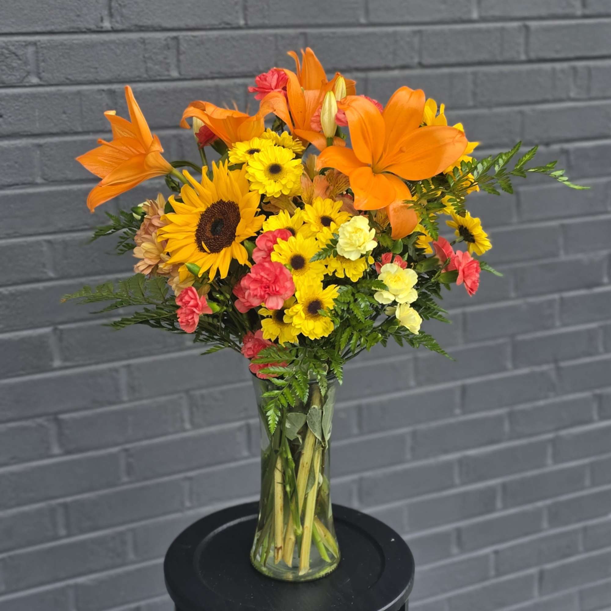 Bright orange lilies take center stage in this cheerful mixed bouquet, making