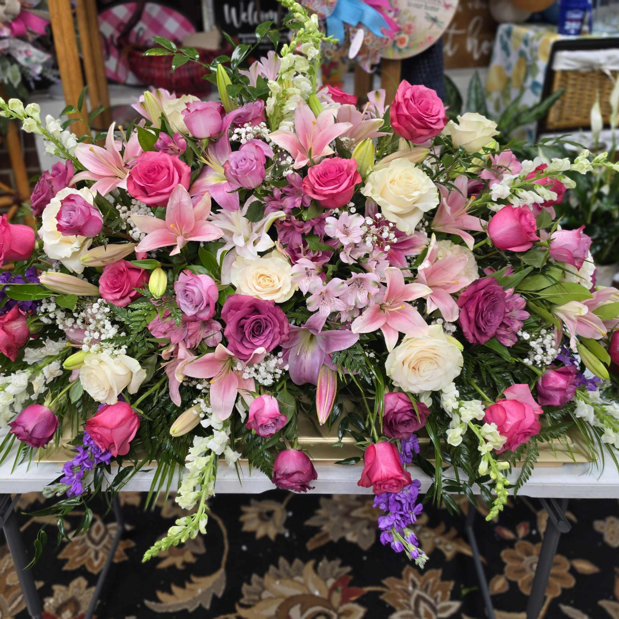 A sweeping casket spray designed for sympathy and memorial services, this large
