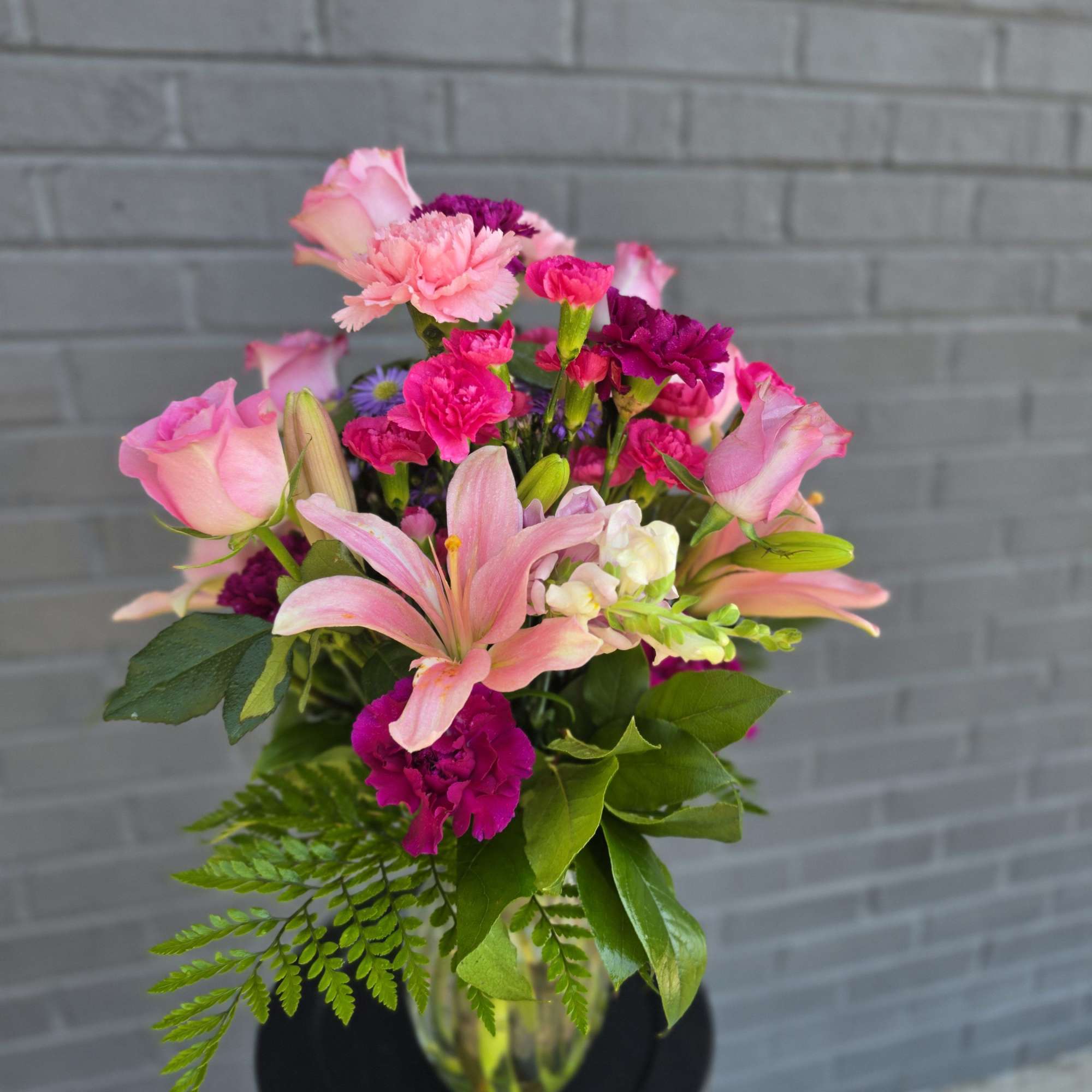 Soft pink lilies, blushing roses, and vivid magenta carnations combine in a