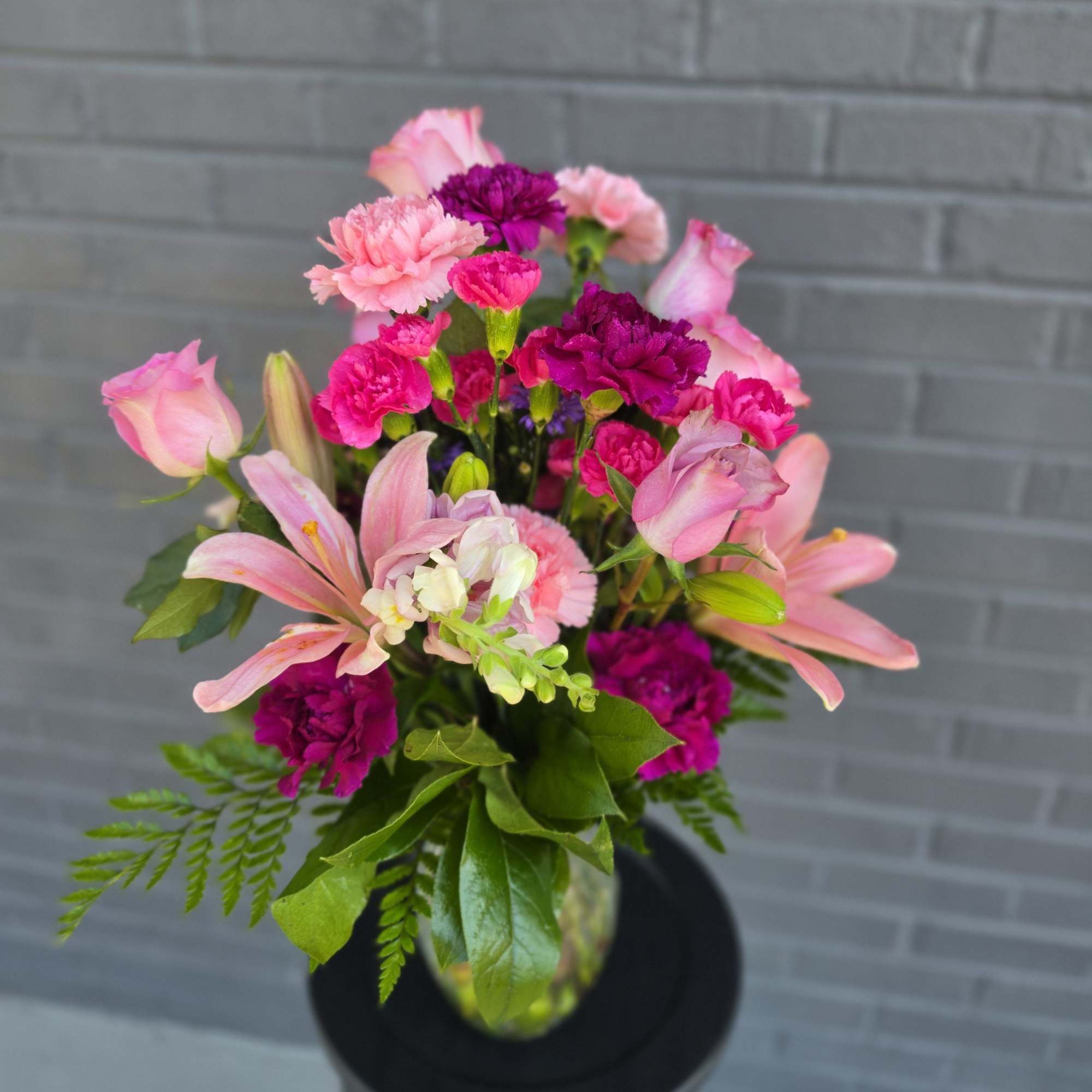Soft pink lilies, blushing roses, and vivid magenta carnations combine in a