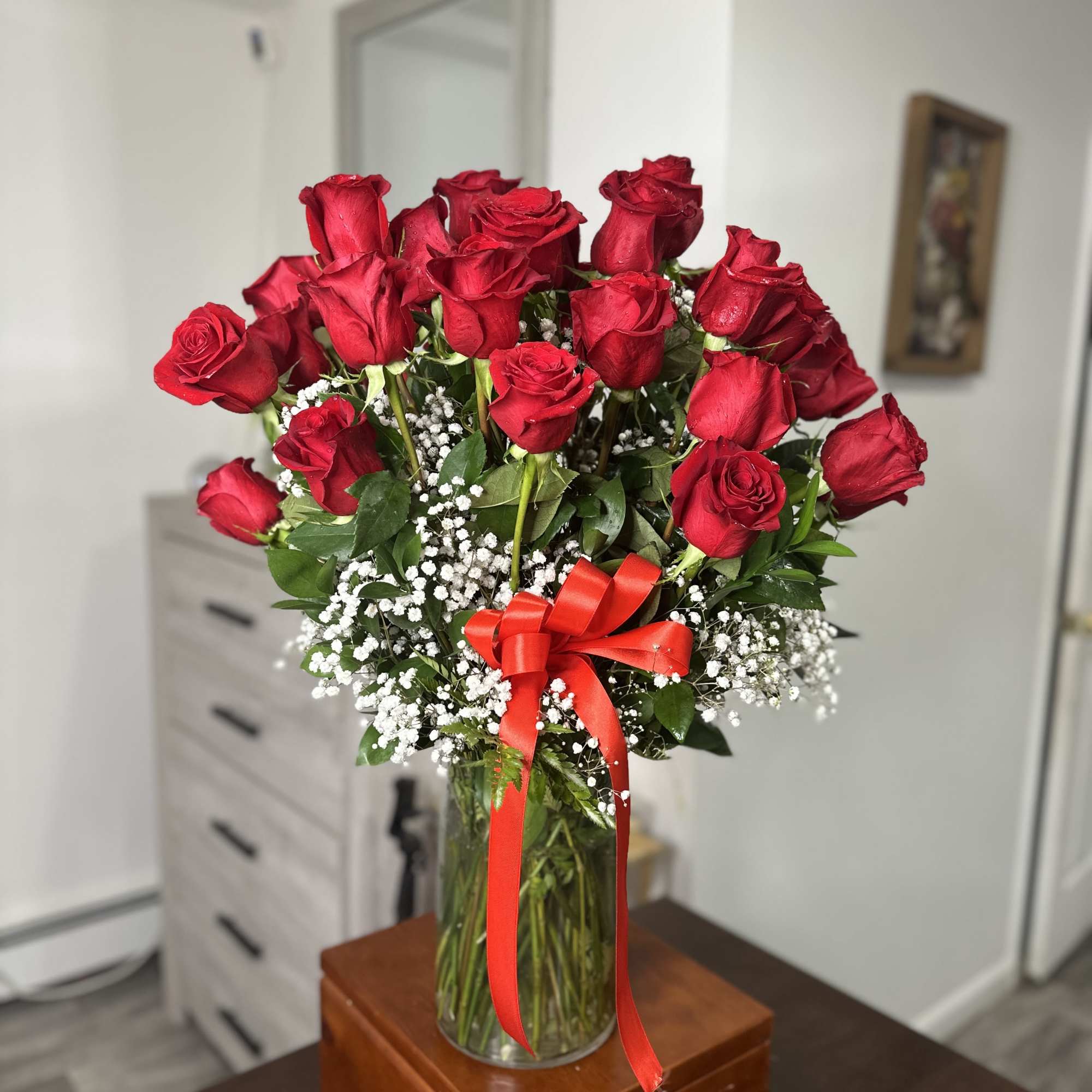 Bouquet of red roses in a glass vase with a red ribbon
