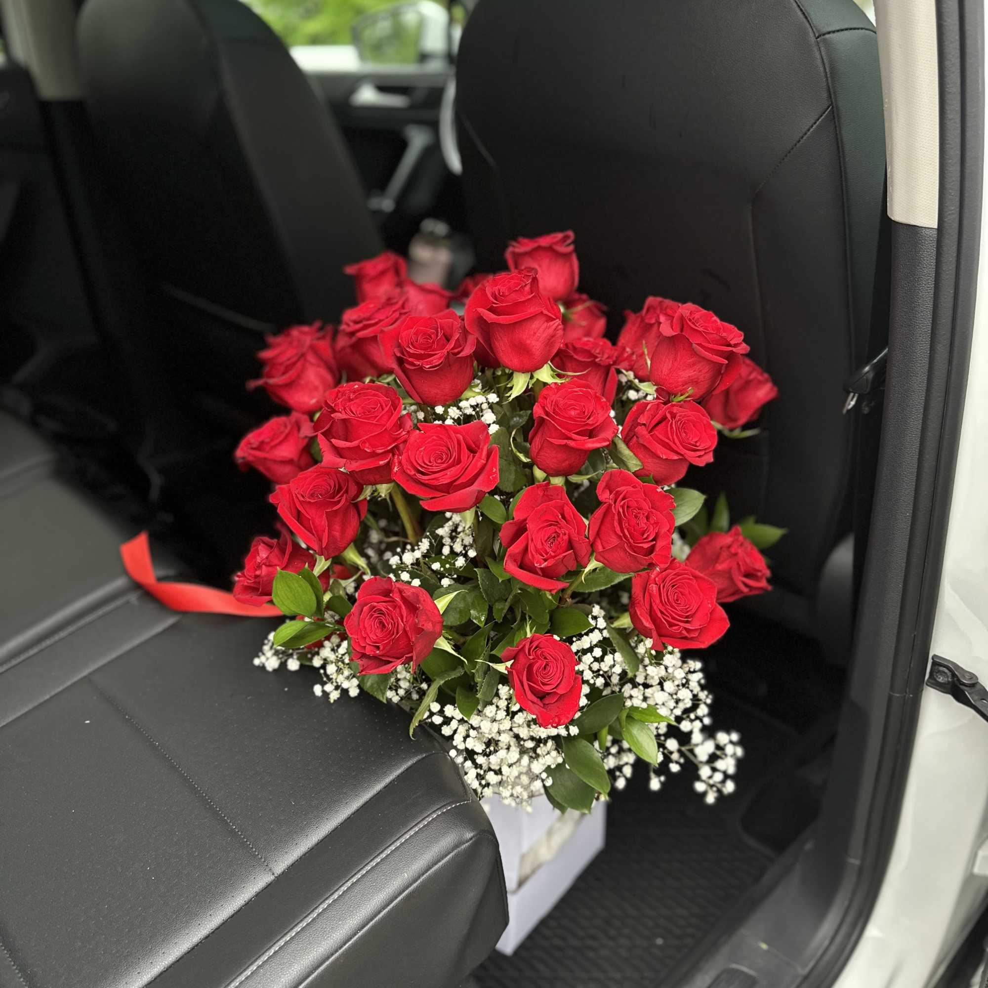 Bouquet of red roses with baby's breath in a car seat