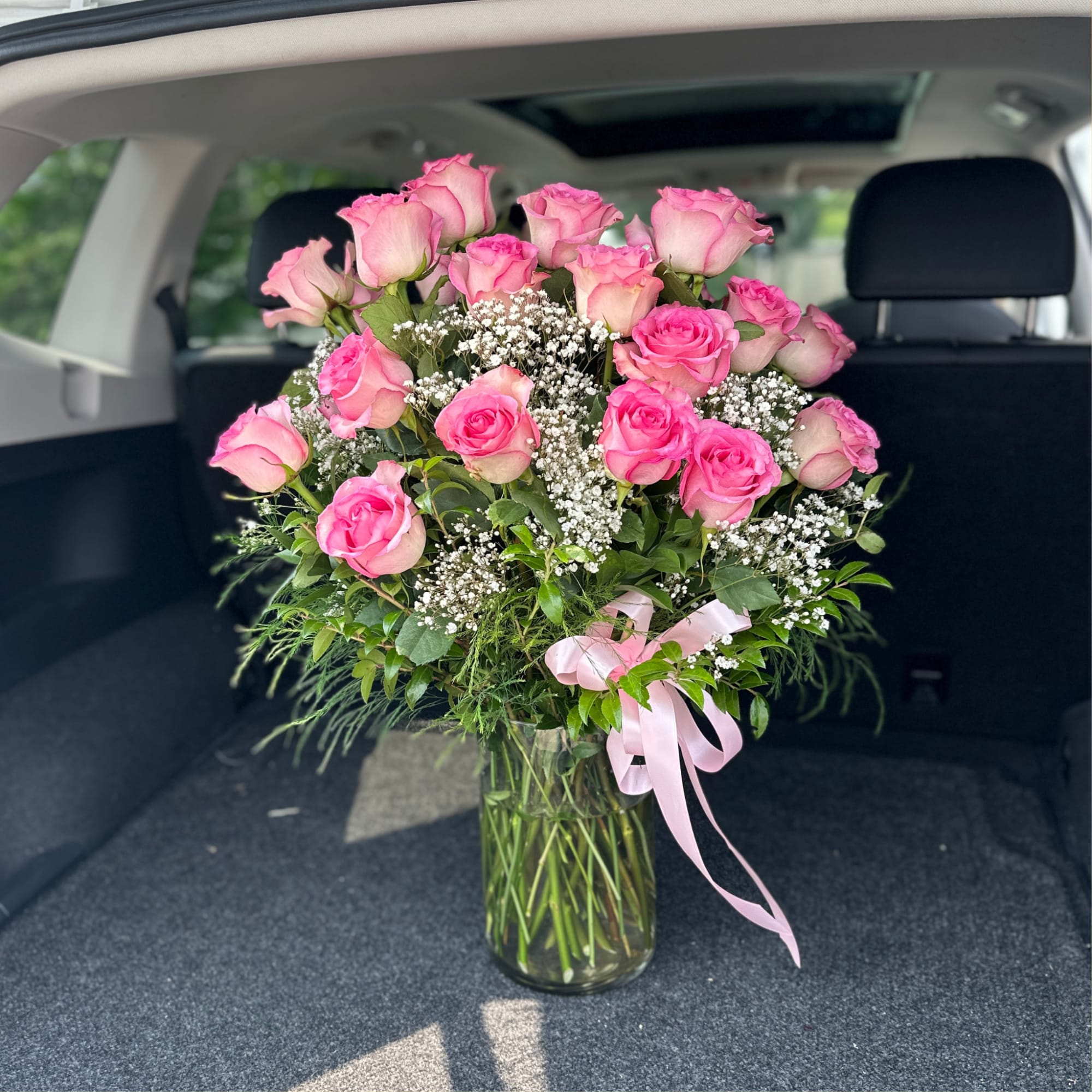 Pink roses arranged in a clear glass vase with baby's breath and a pink ribbon, photo 3 of 4