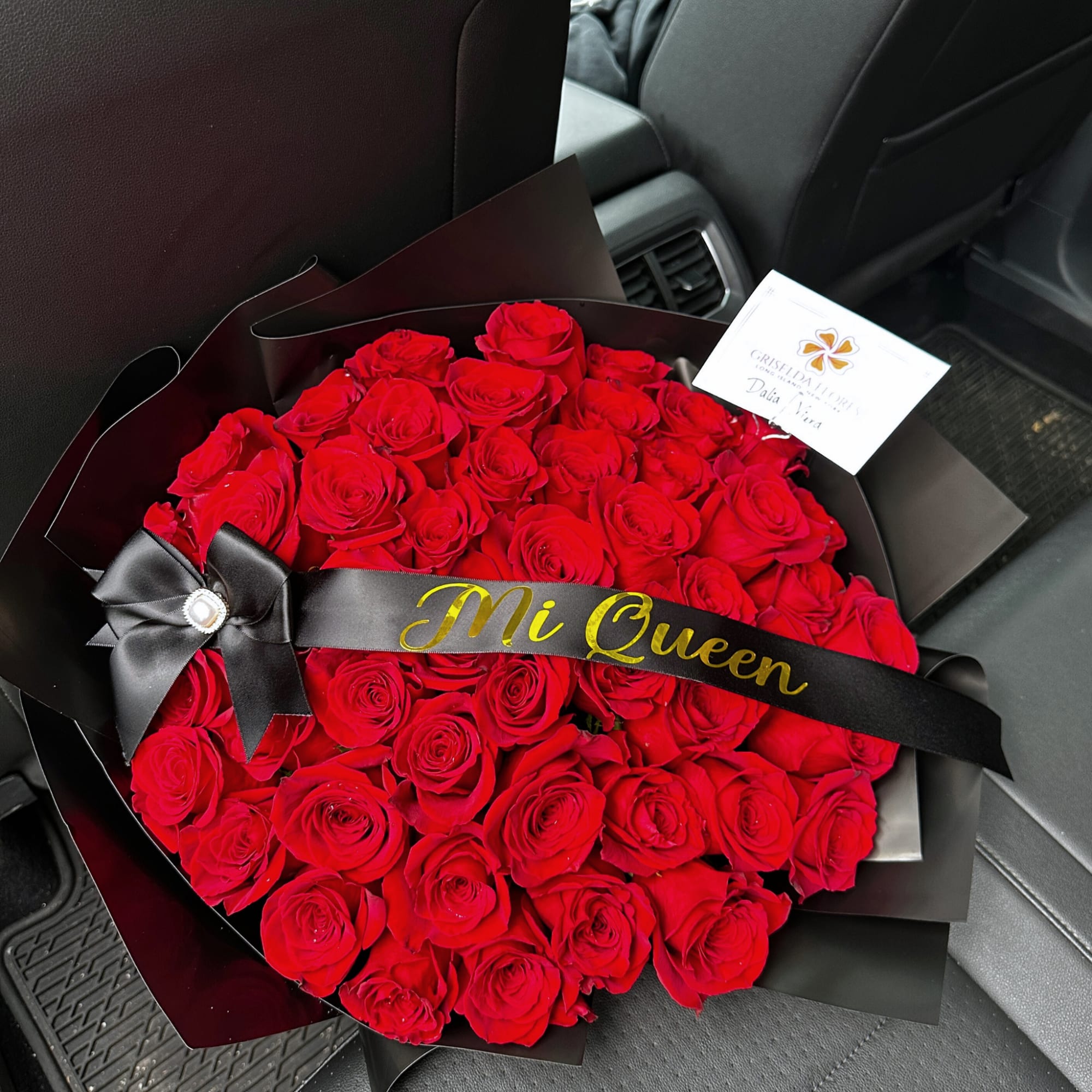 Large bouquet of red roses wrapped in black paper with a ribbon
