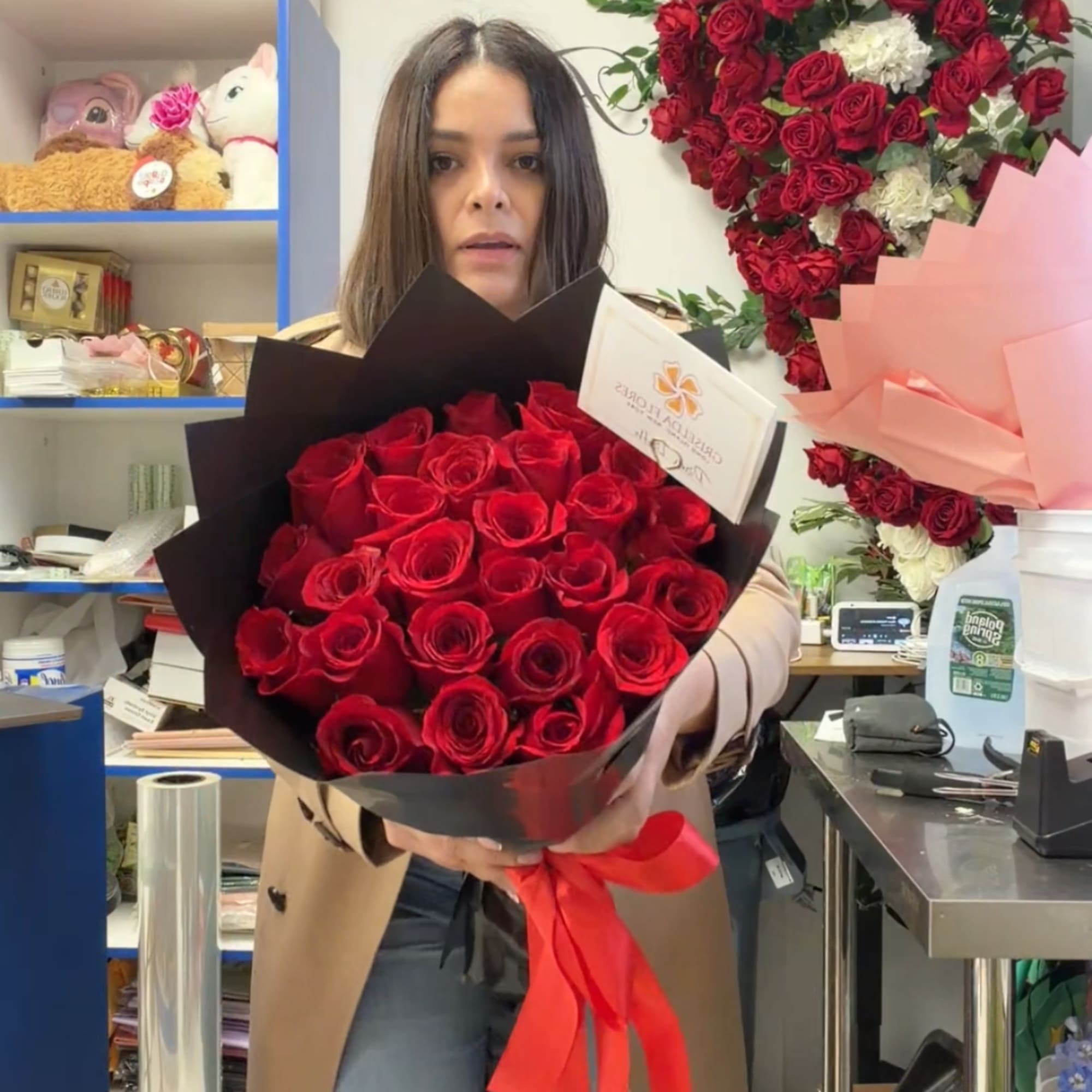 Woman holding a bouquet of red roses wrapped in black paper with a red ribbon