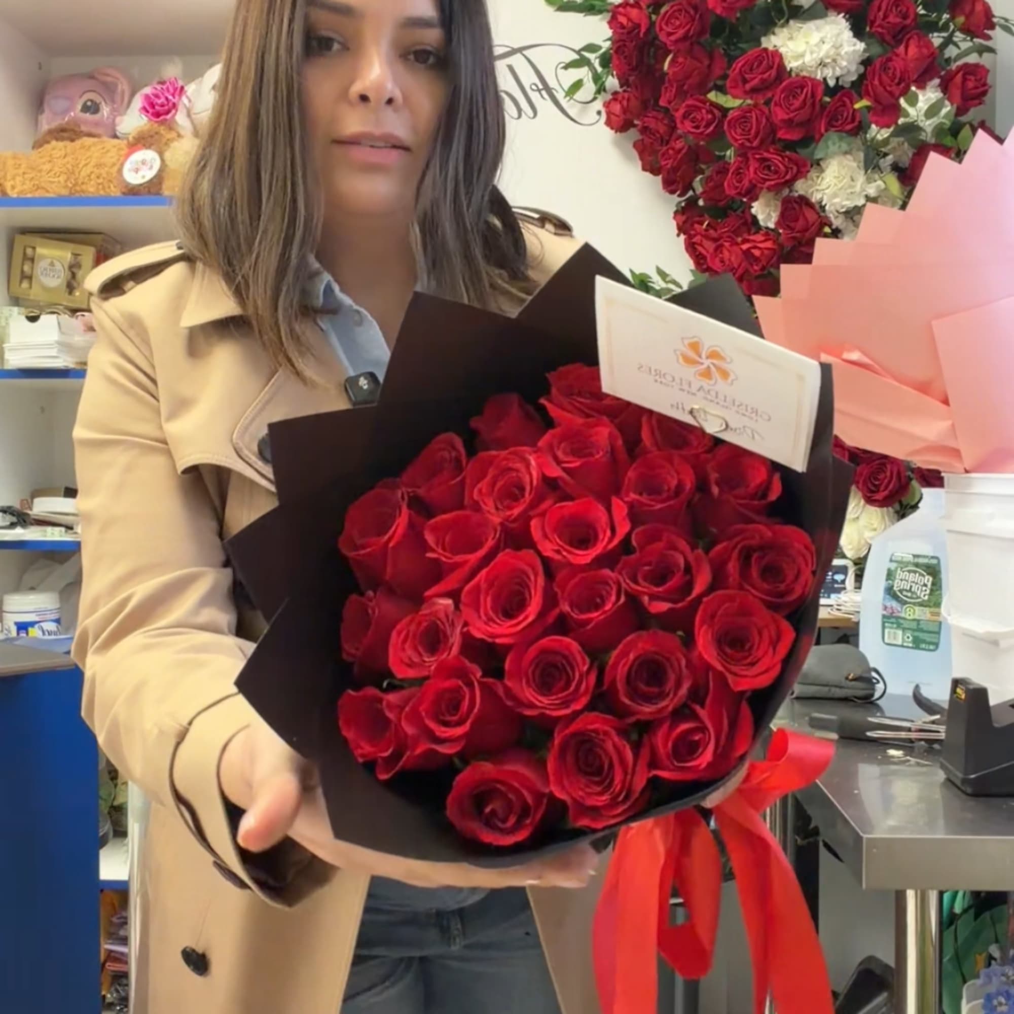 Woman holding a bouquet of red roses wrapped in black paper with a red ribbon, photo 2 of 3