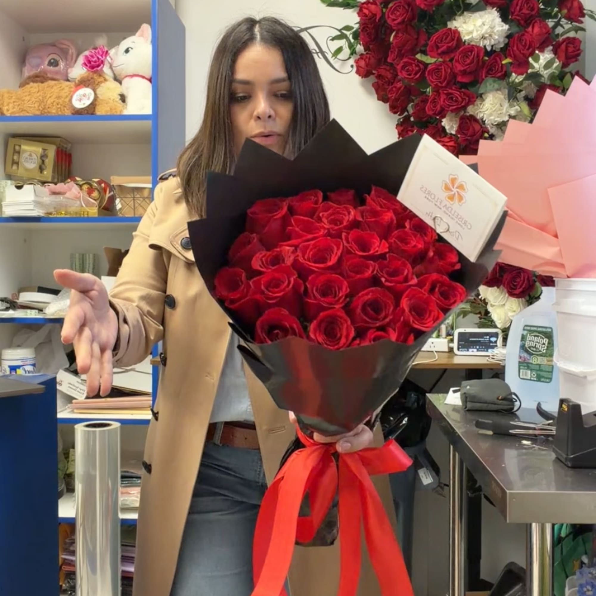 Woman holding a bouquet of red roses wrapped in black paper with a red ribbon.