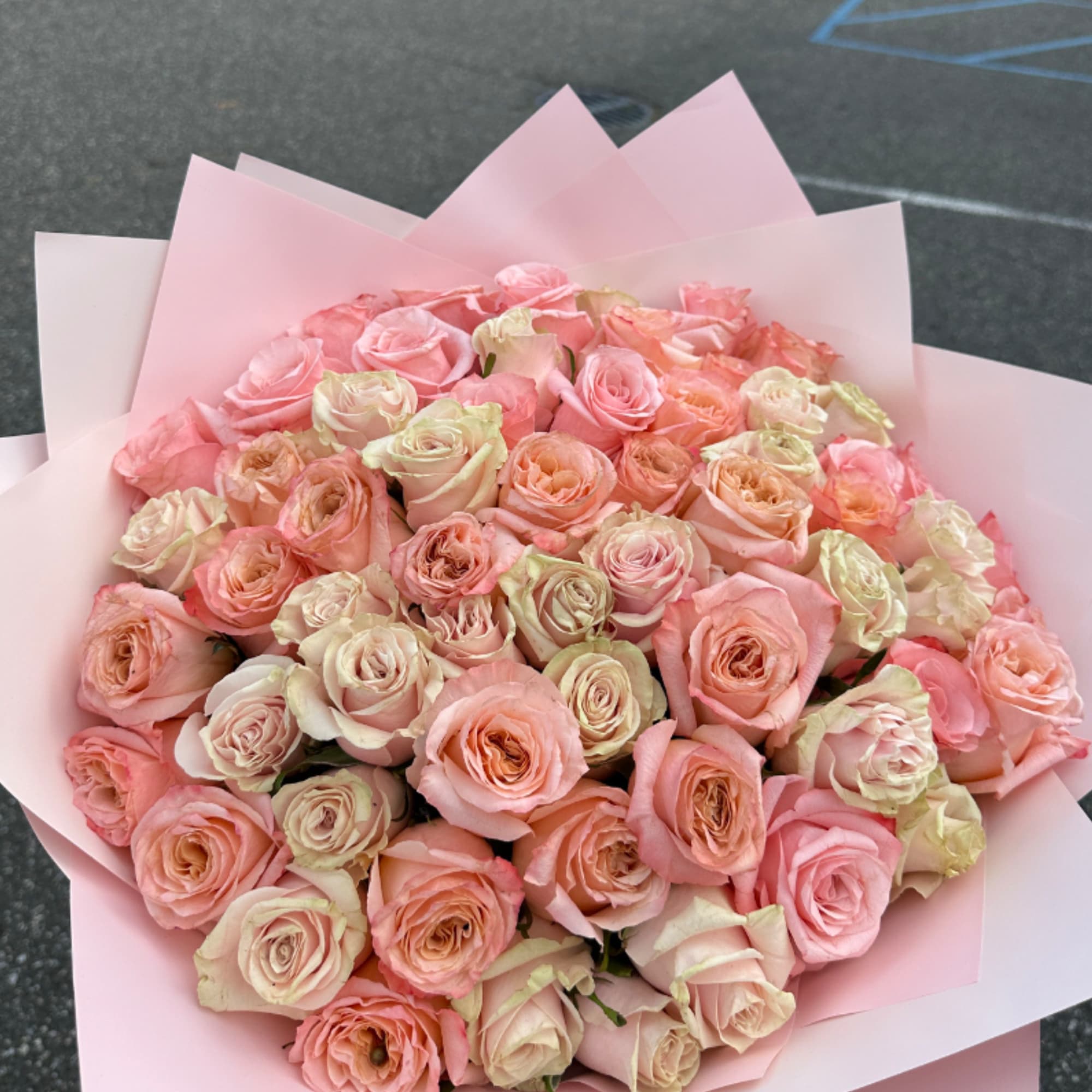 Large bouquet of pale pink and peach roses wrapped in pink paper