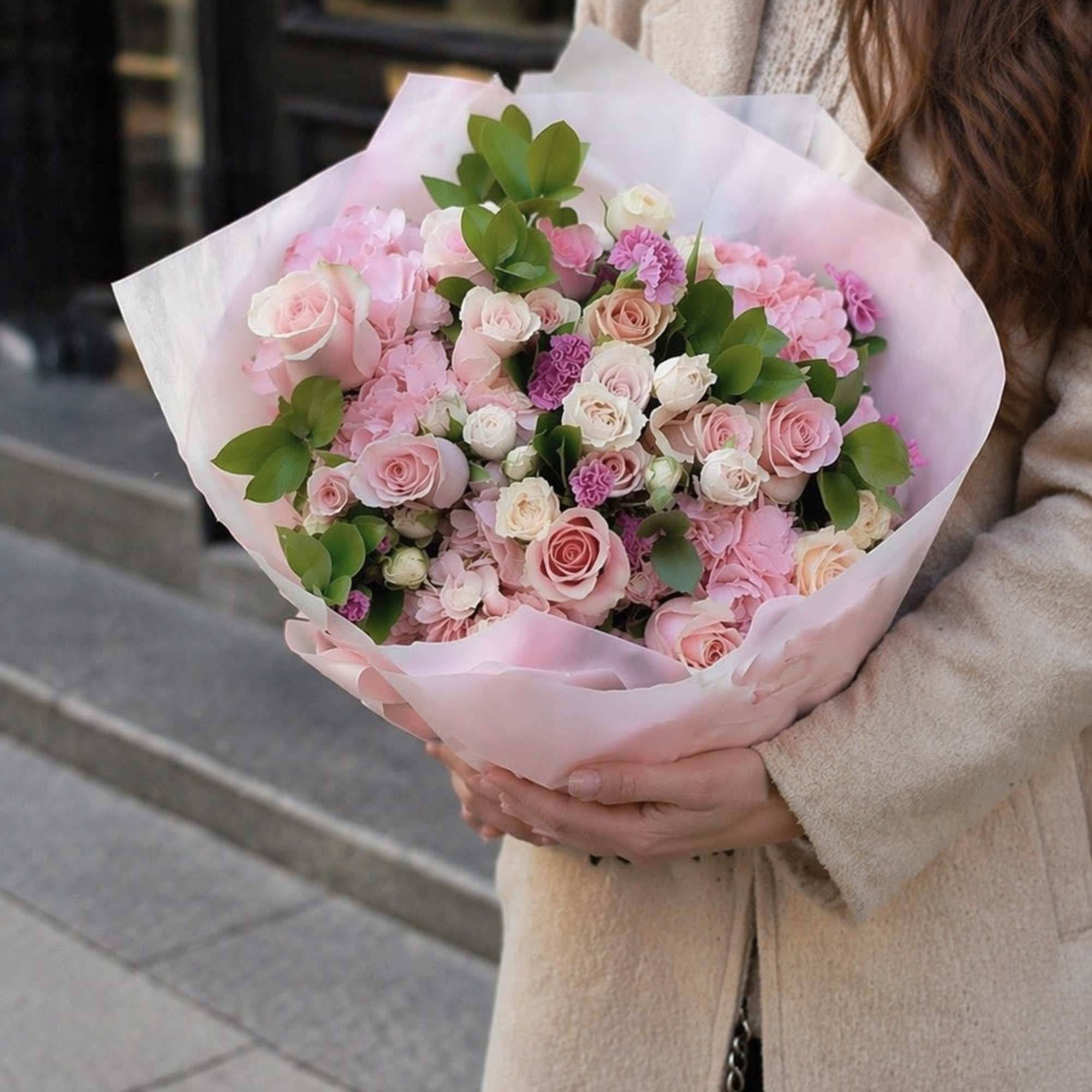 A lush, rounded hand-tied bouquet in soft shades of blush pink, cream