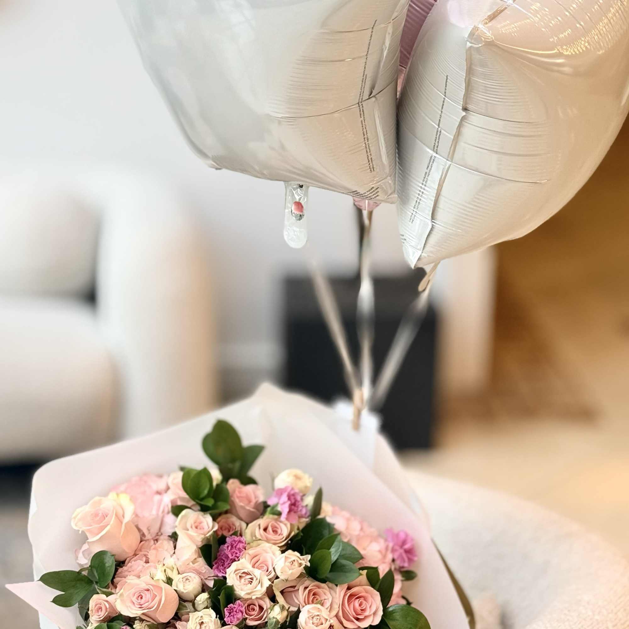 A lush, rounded hand-tied bouquet in soft shades of blush pink, cream