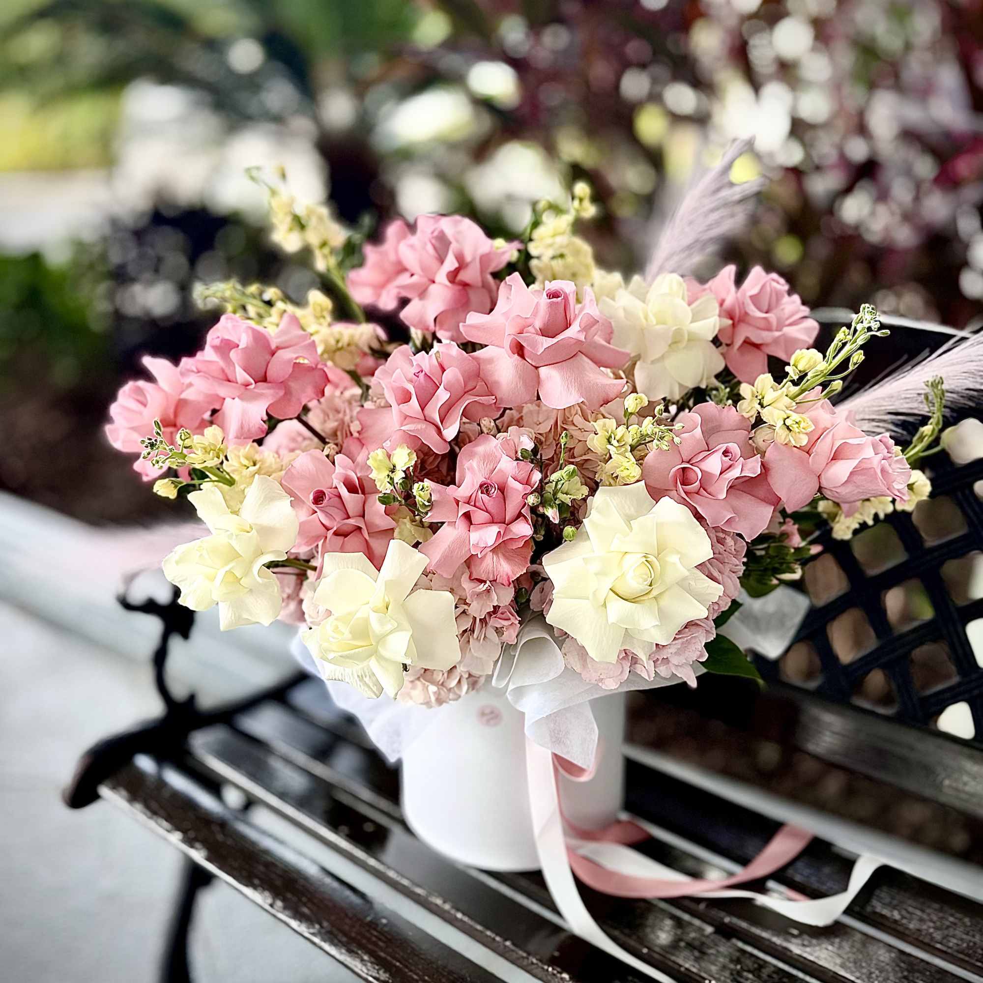 A floral box designed with white and pink roses, stock, and seasonal