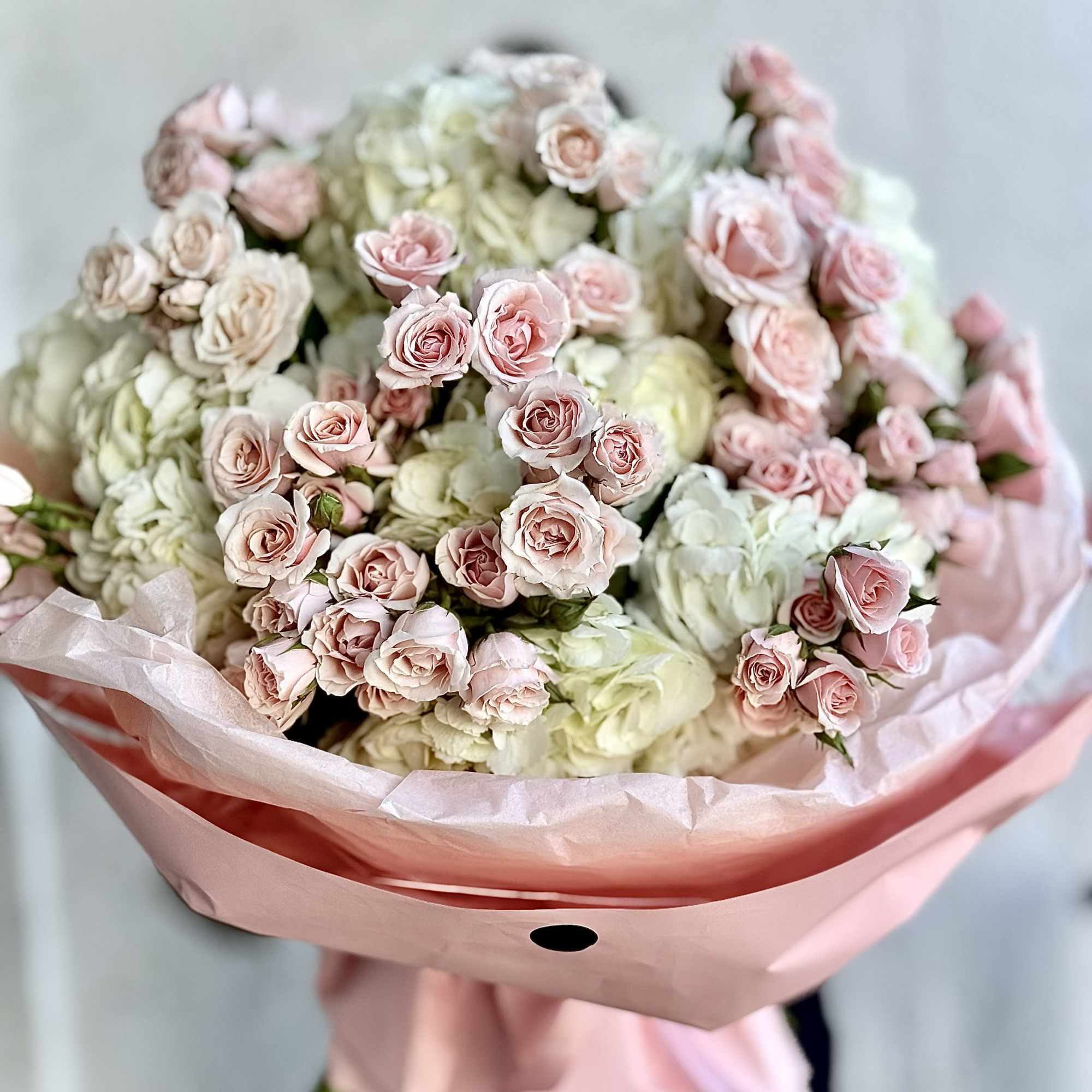 Soft clusters of pale pink spray roses nestled against voluminous white hydrangea