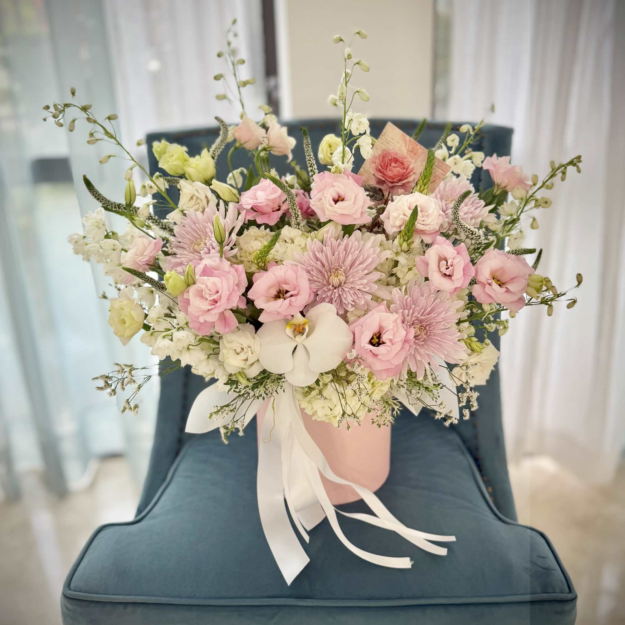 A soft, garden-fresh bouquet arranged in a pink hat box-this flower arrangement