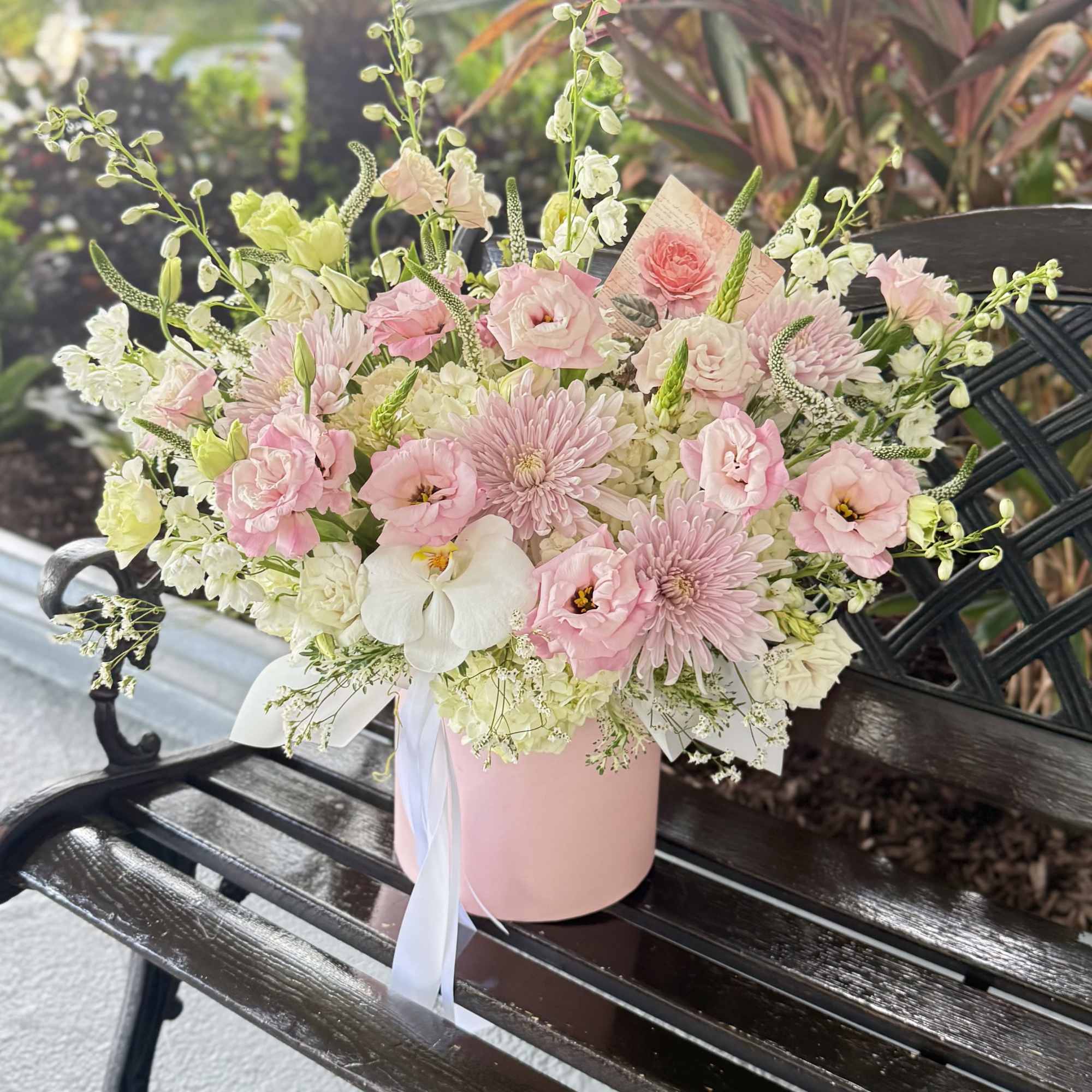 A soft, garden-fresh bouquet arranged in a pink hat box-this flower arrangement