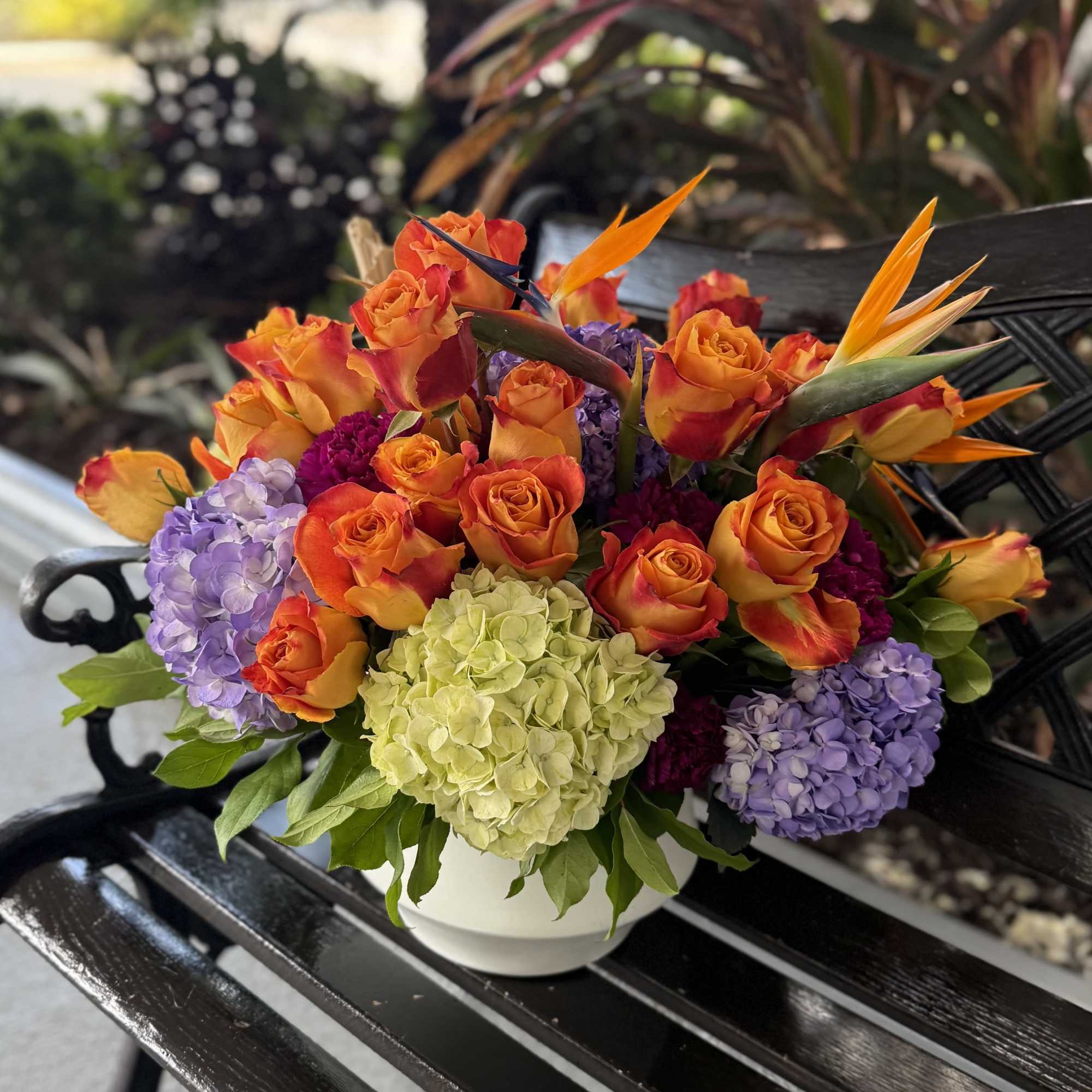 A vibrant cluster of orange-and-red roses and jewel-toned hydrangeas gives this flower