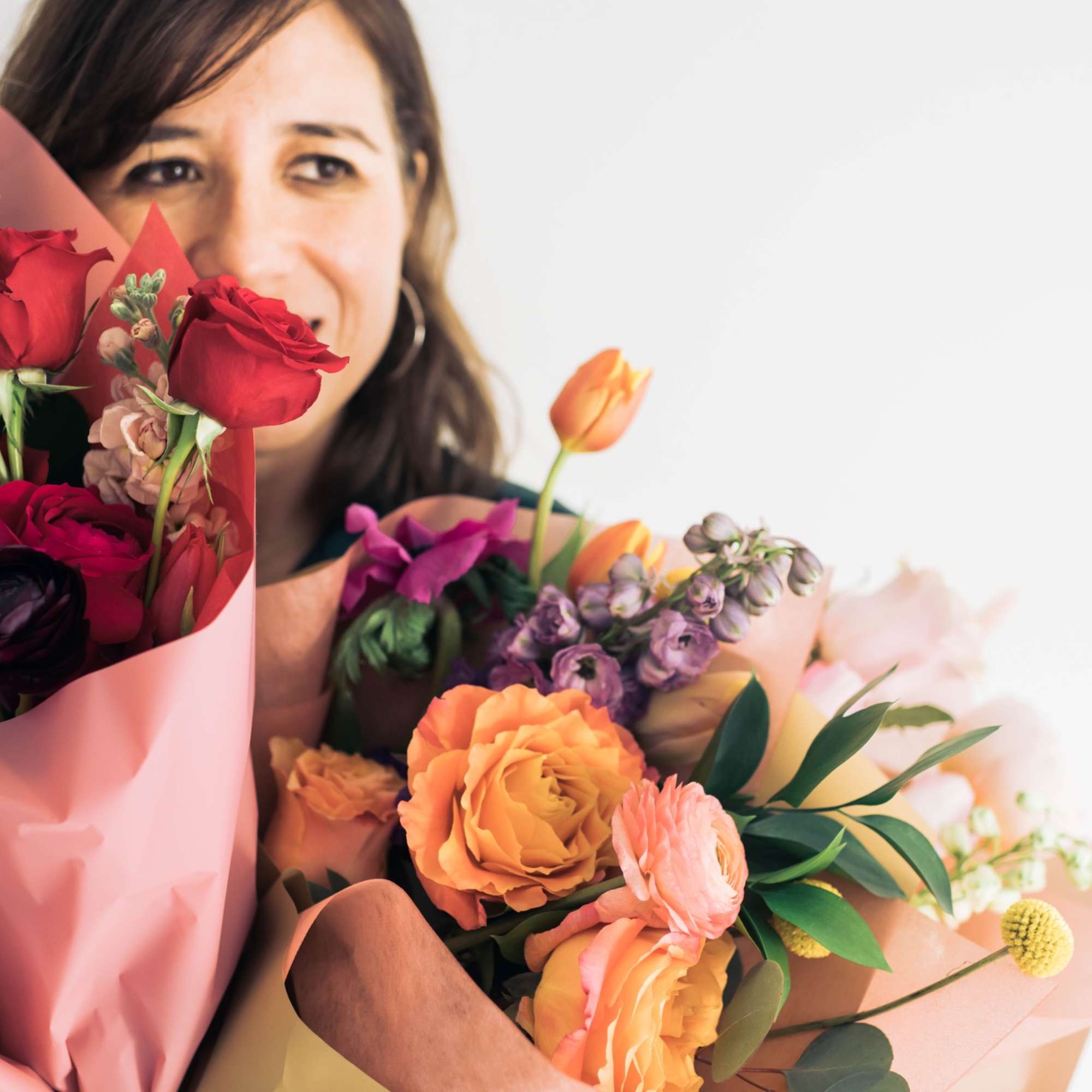 Woman holding two colorful bouquets of roses and mixed flowers