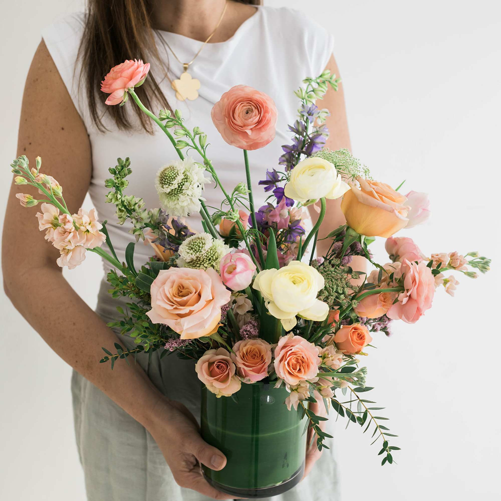 Mixed bouquet in a green vase with peach, pink, yellow, and purple flowers