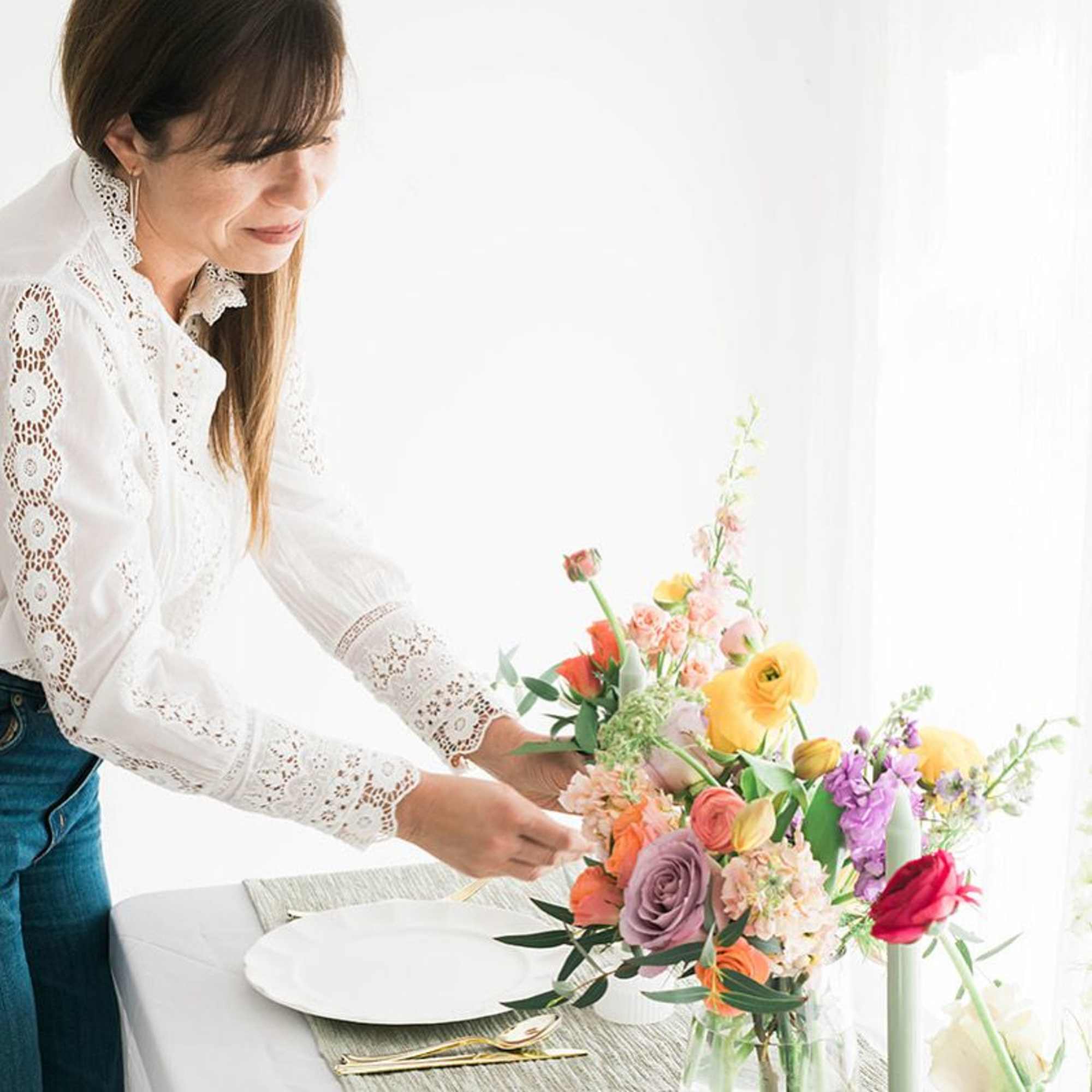 Woman arranging a colorful bouquet in a clear glass vase