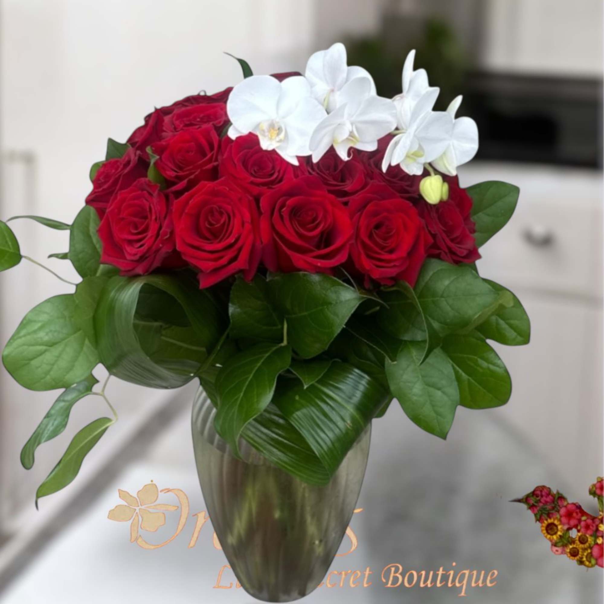 Red roses and white orchids arranged in a glass vase