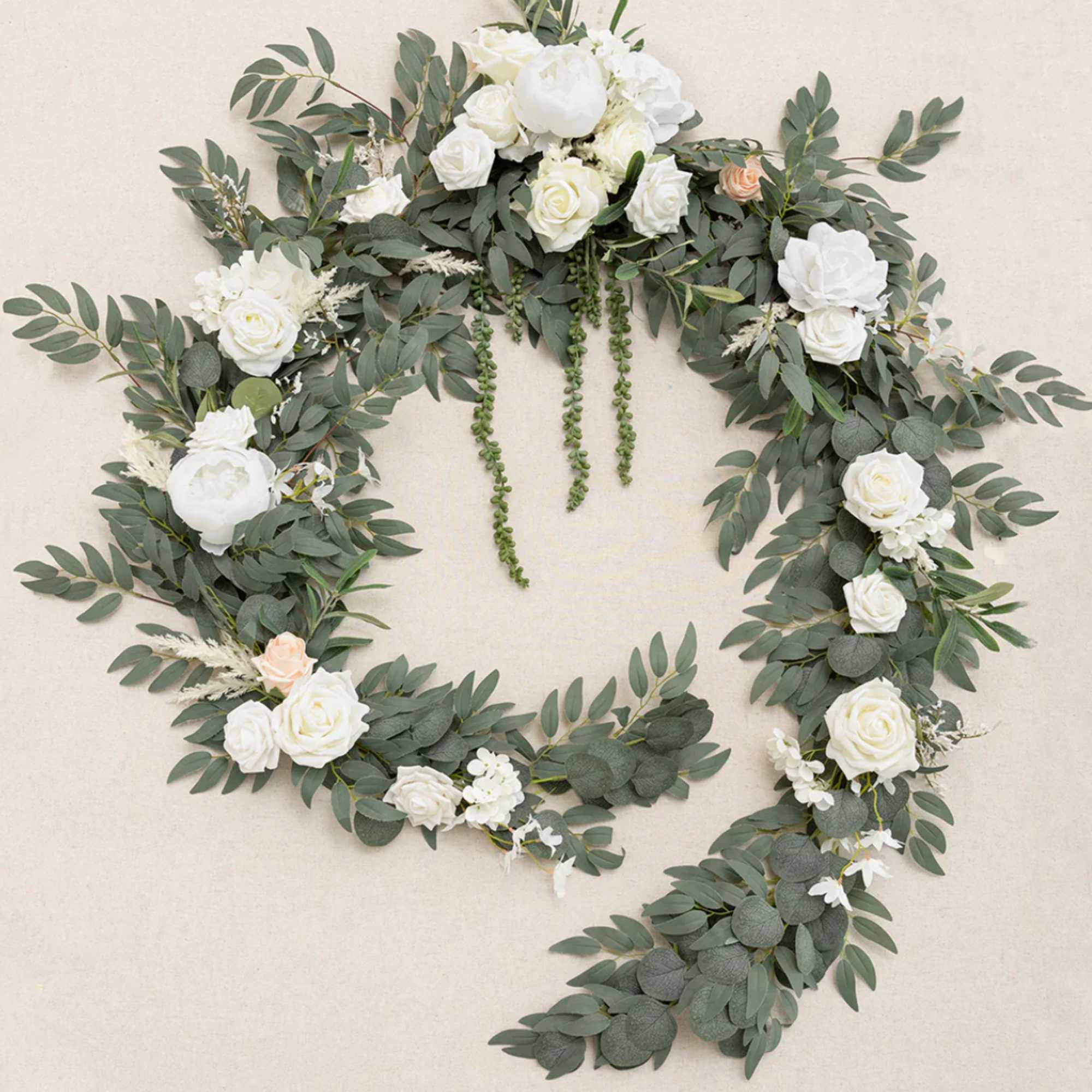 Large open wreath of cascading greenery with white roses and peonies and a touch of peach blooms