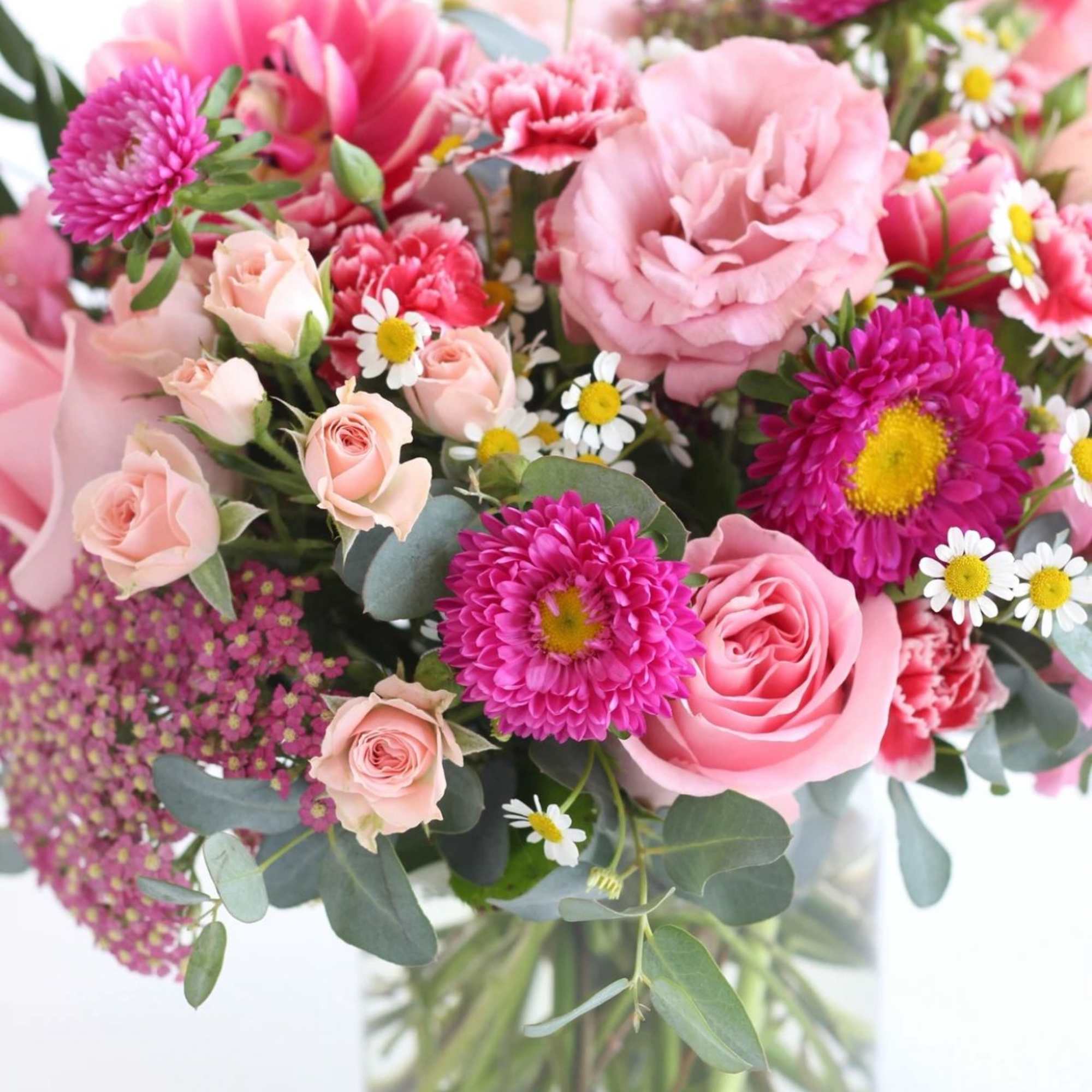 Pink and white mixed flower arrangement with roses and daisies in a clear glass vase