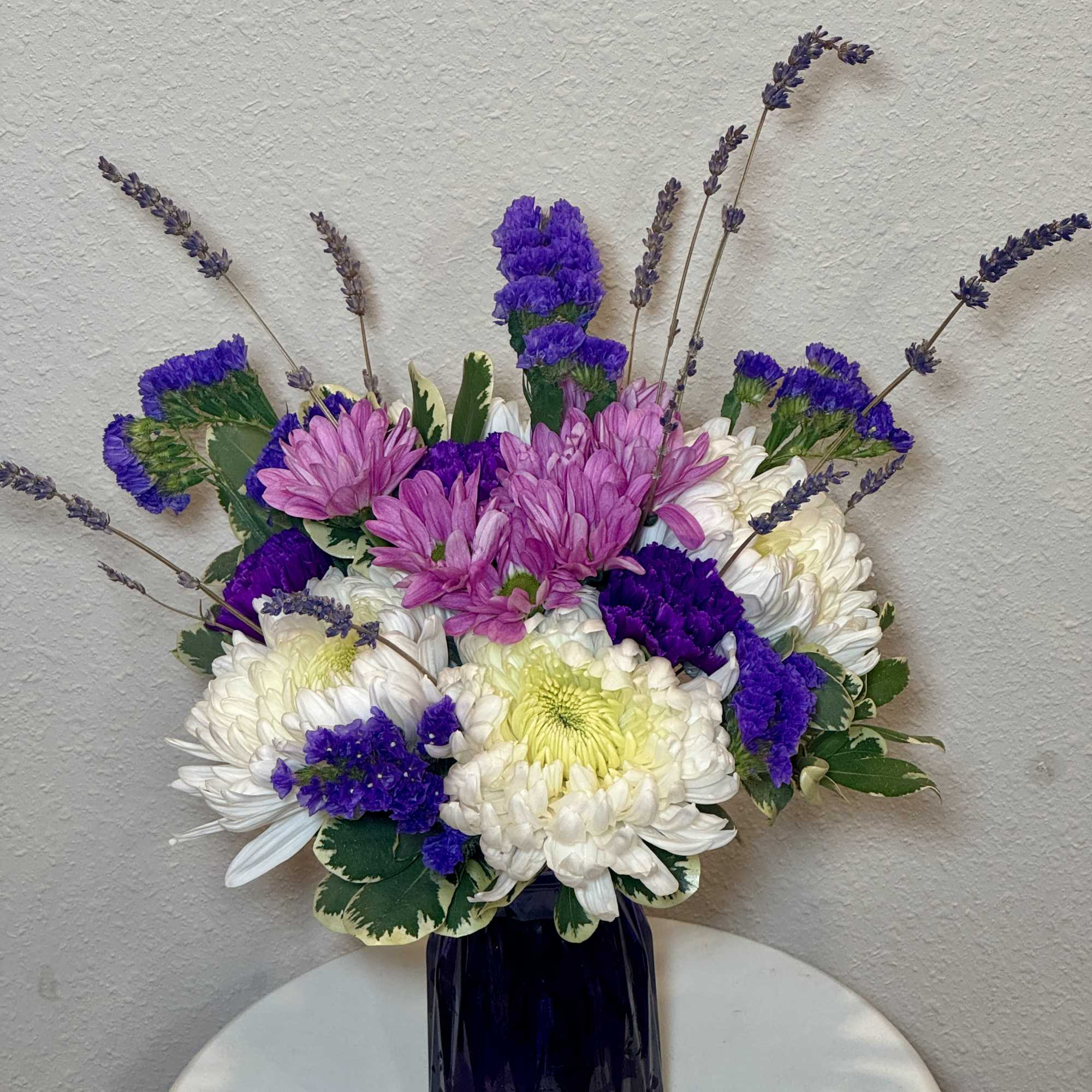 Purple and white chrysanthemum bouquet in a dark vase