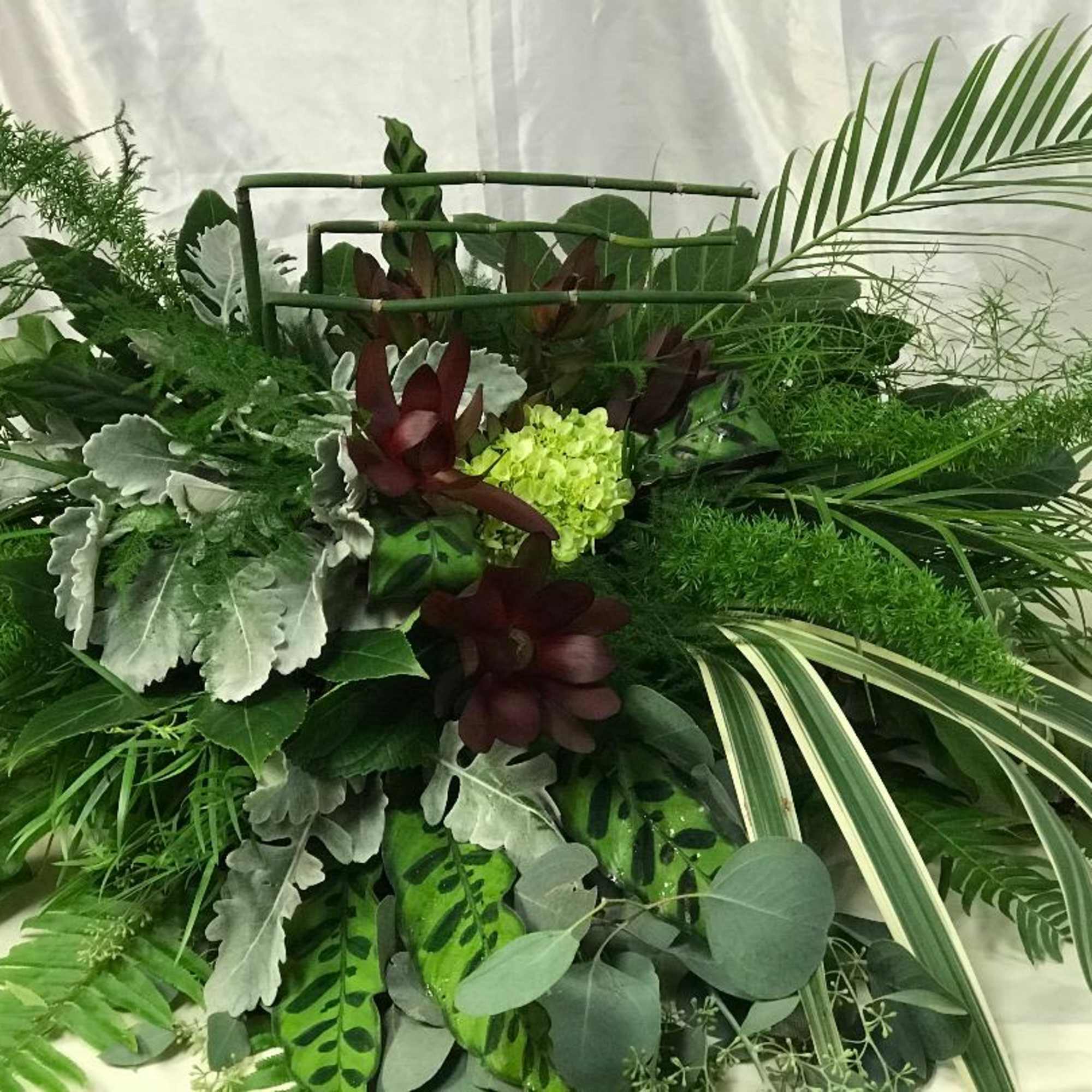 Large green tropical foliage arrangement with burgundy accents