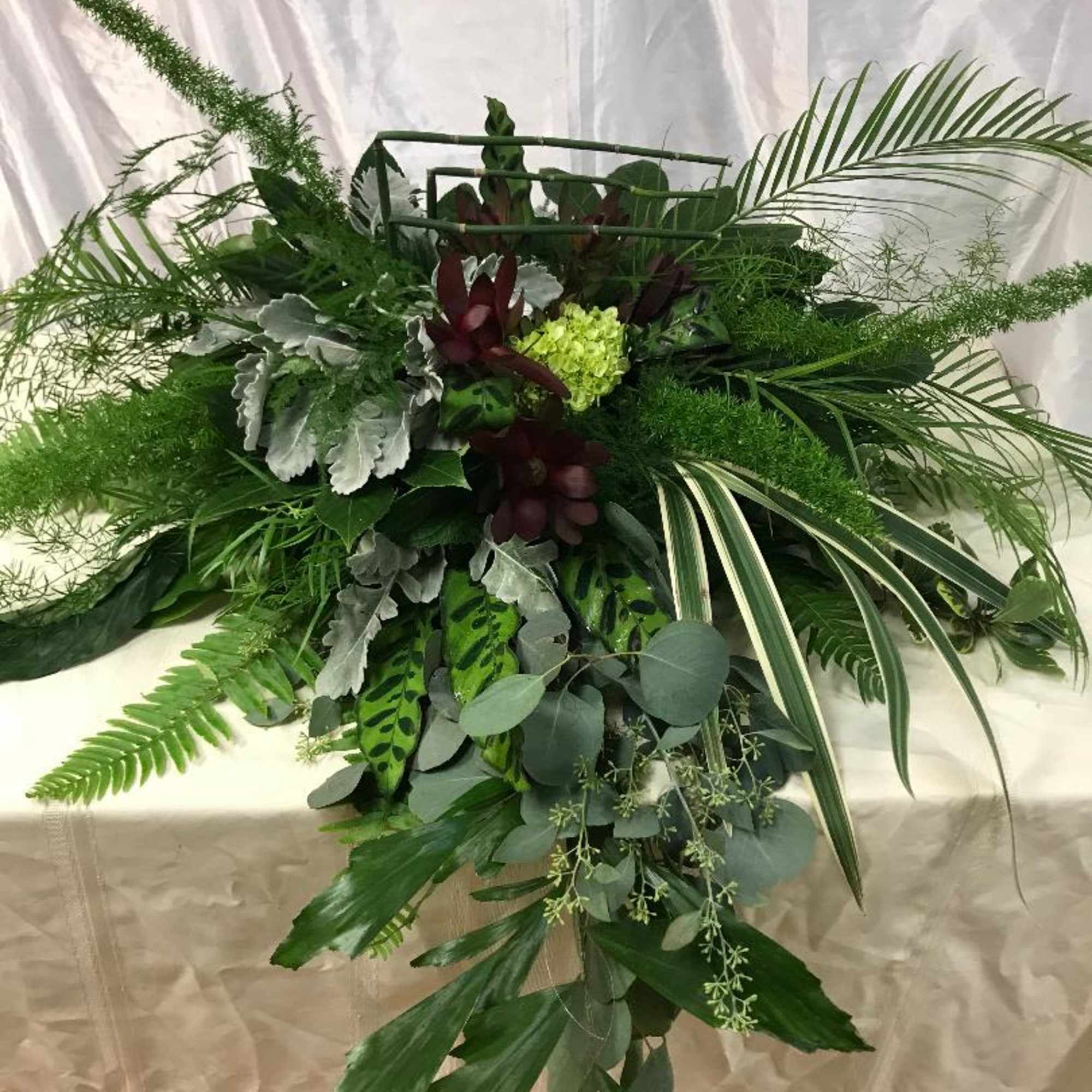 Large green floral spray with tropical foliage and a few burgundy accents