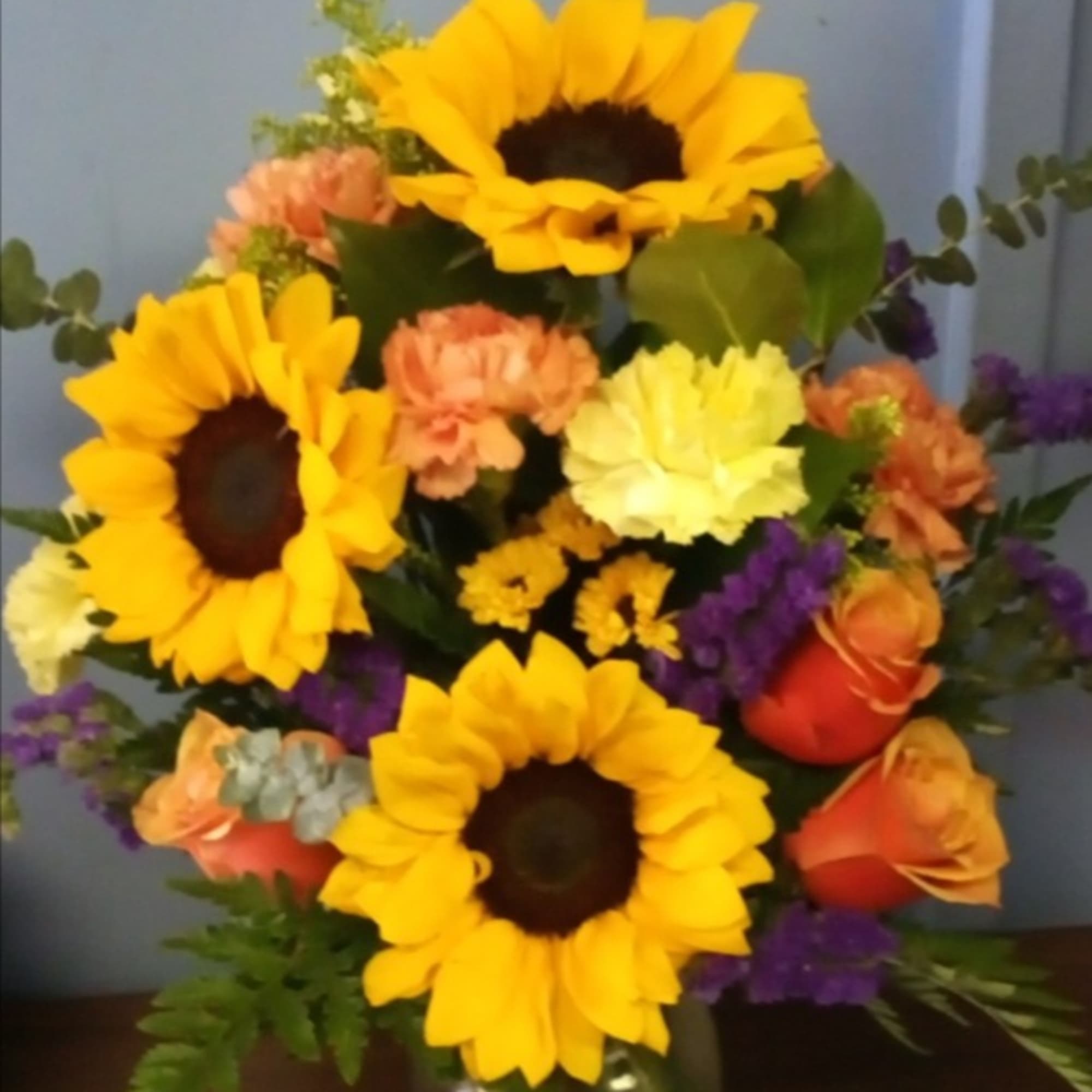 Golden sunflowers steal the show in this mixed-color flower arrangement, a cheerful