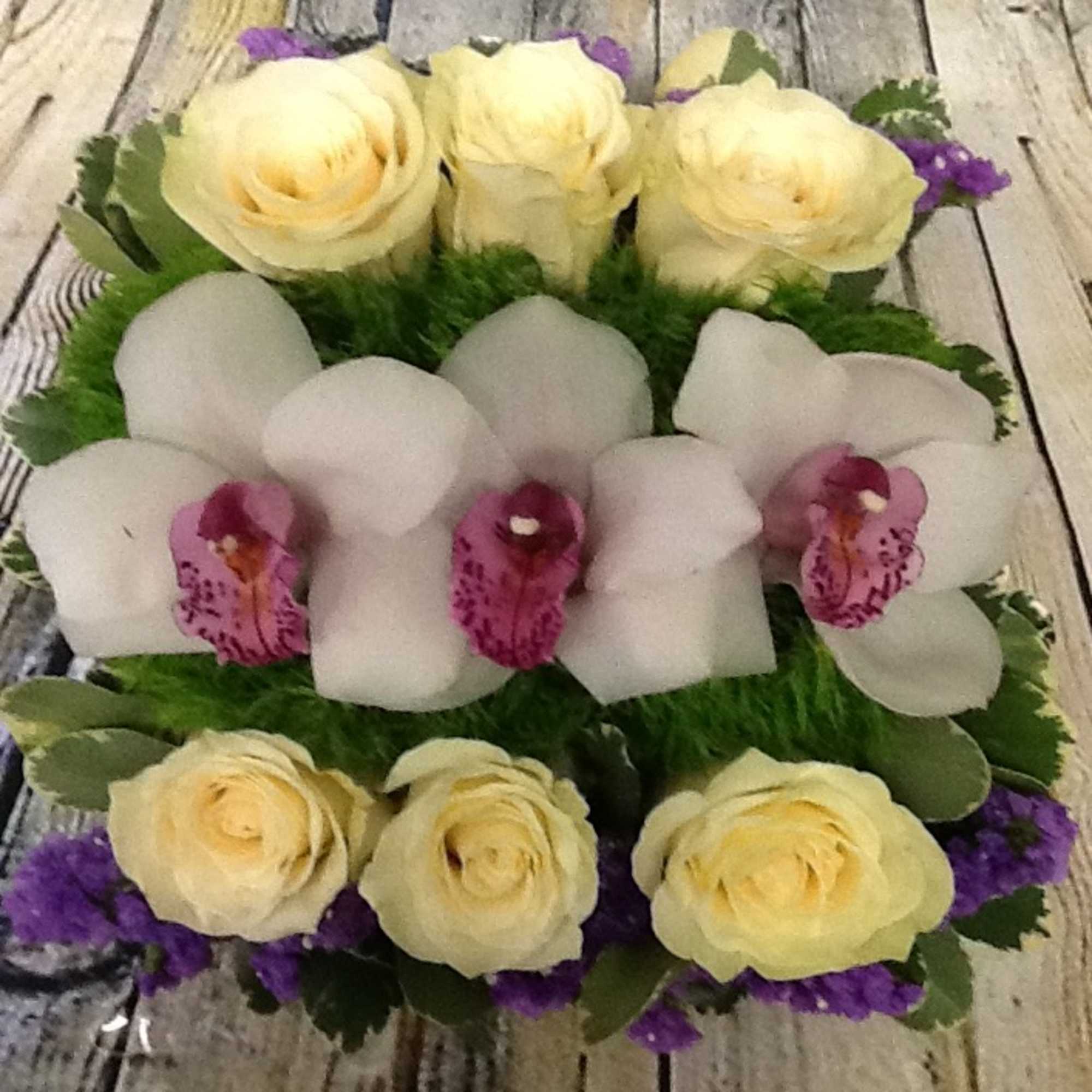 Cream roses and white orchids arranged in a round bouquet