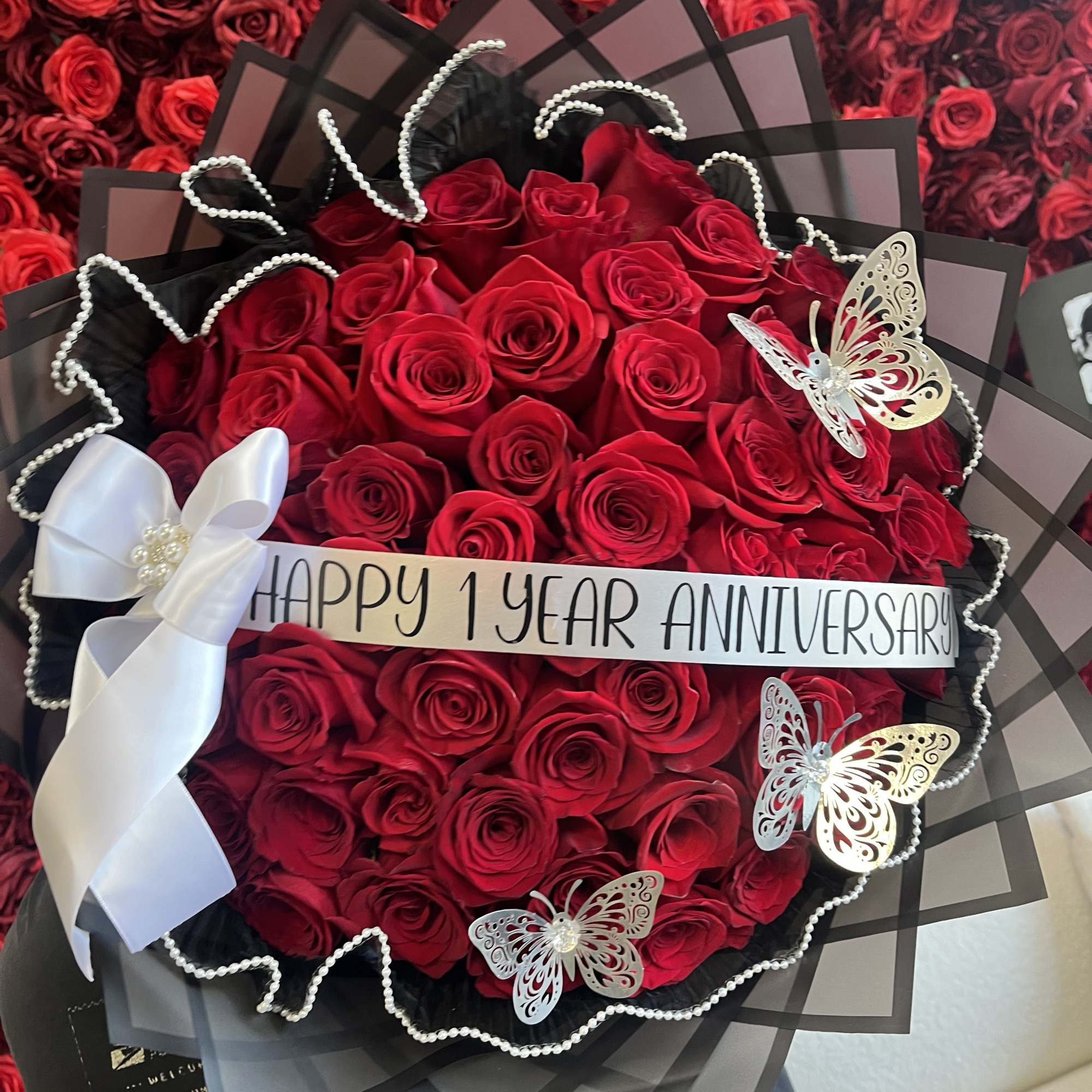Bouquet of red roses with a white anniversary ribbon and butterfly decorations