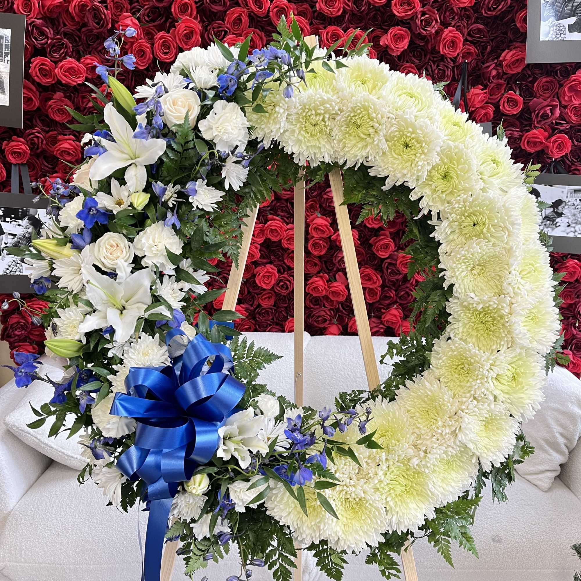Heart-shaped floral wreath with white and blue flowers on an easel