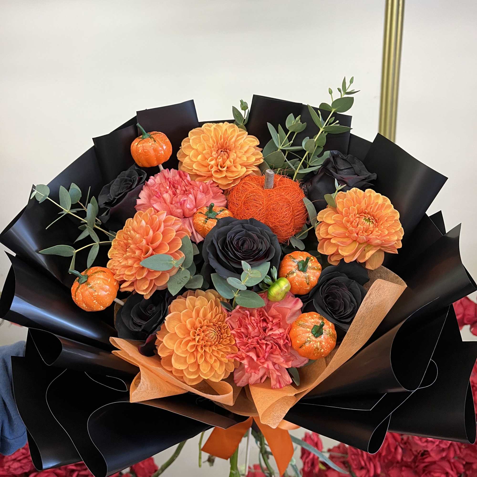 Bouquet of orange and black flowers with small pumpkin accents