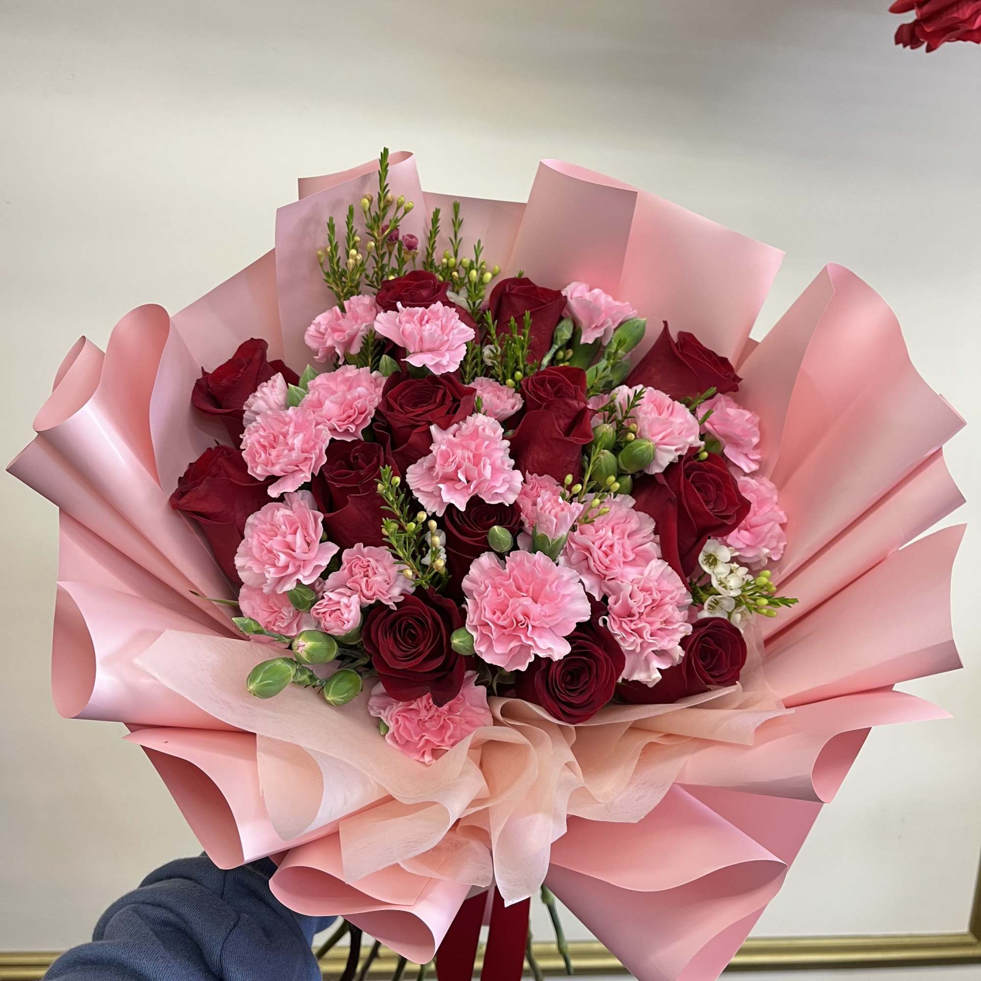 Bouquet of red roses and pink carnations wrapped in pink paper