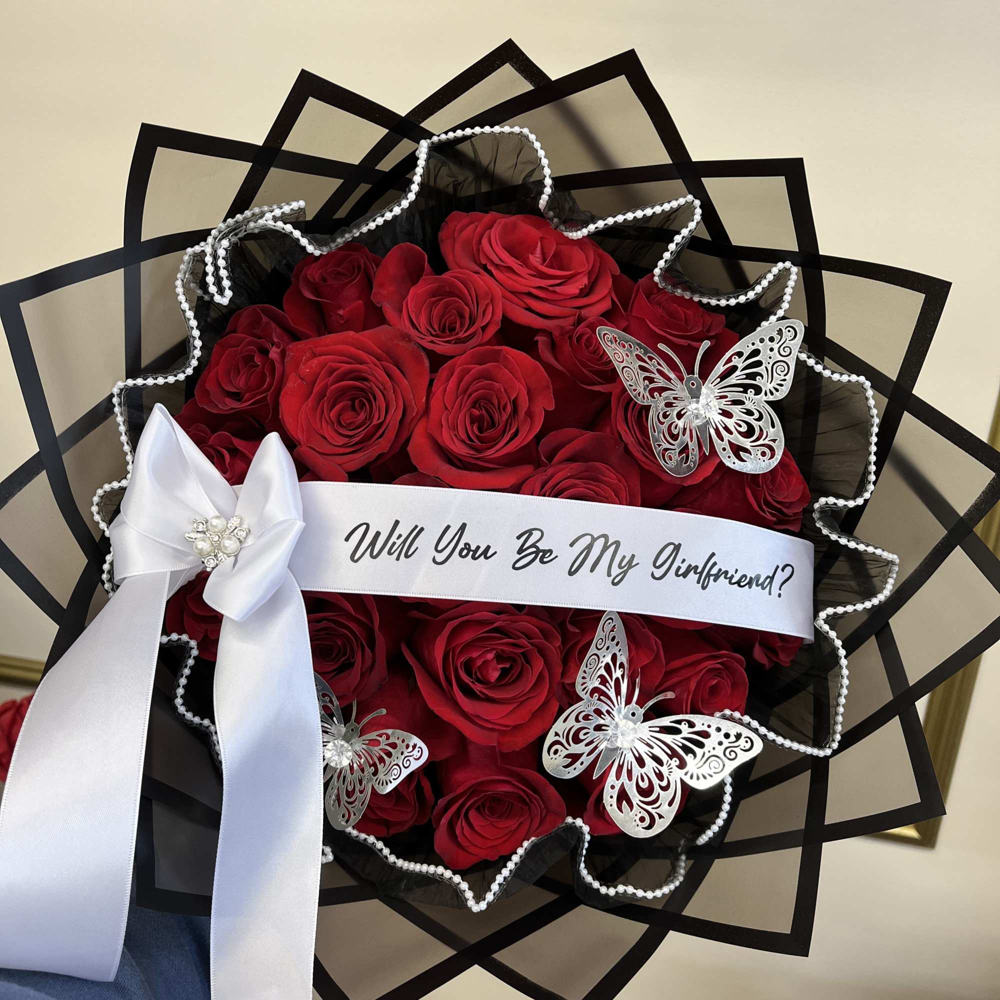 Bouquet of red roses with a white ribbon and butterfly decorations