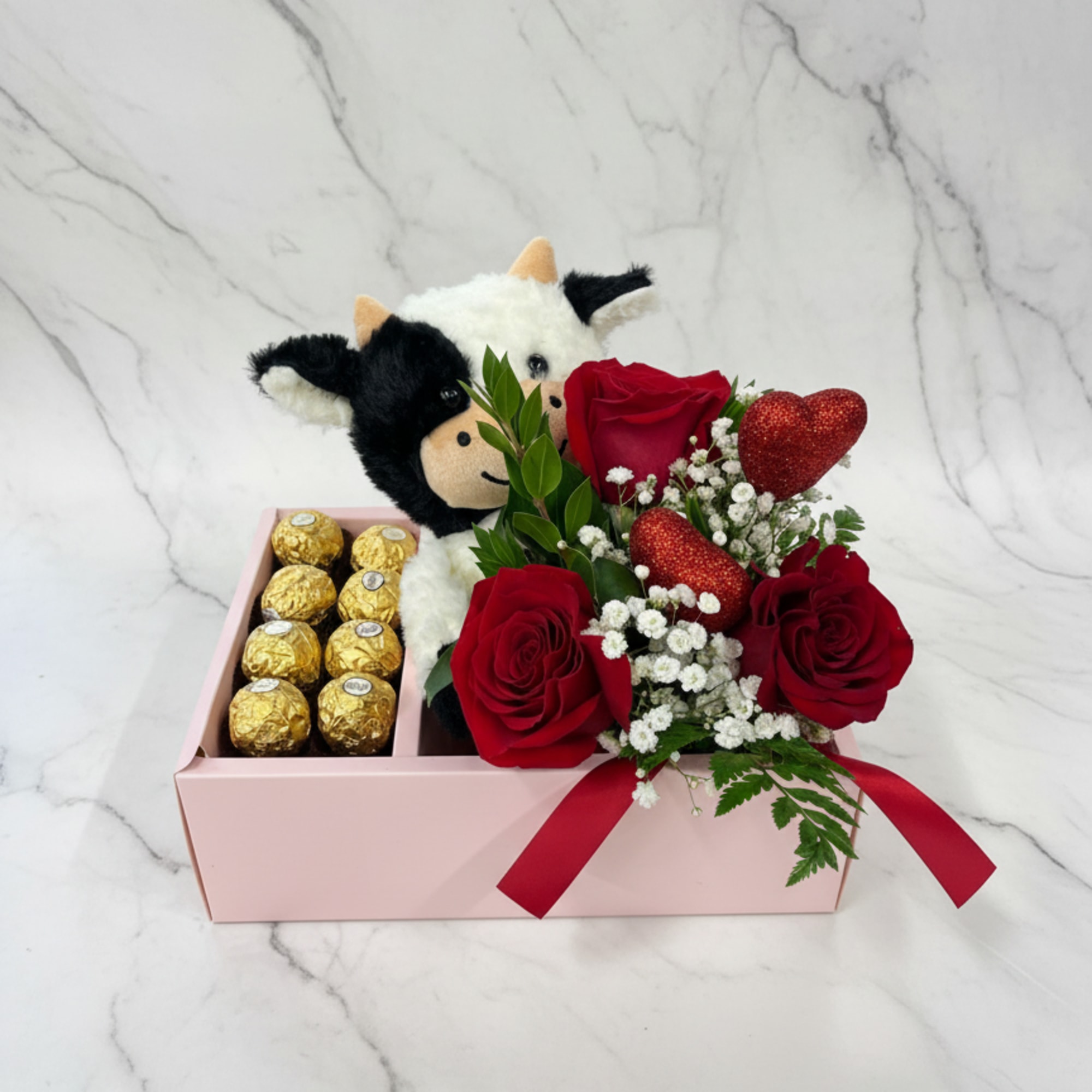 Red roses with chocolates and a plush cow in a pink gift box