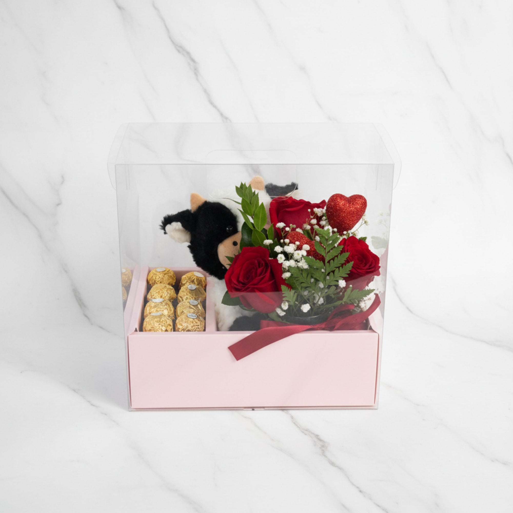 Gift box with red roses, chocolates, and a teddy bear under a clear lid