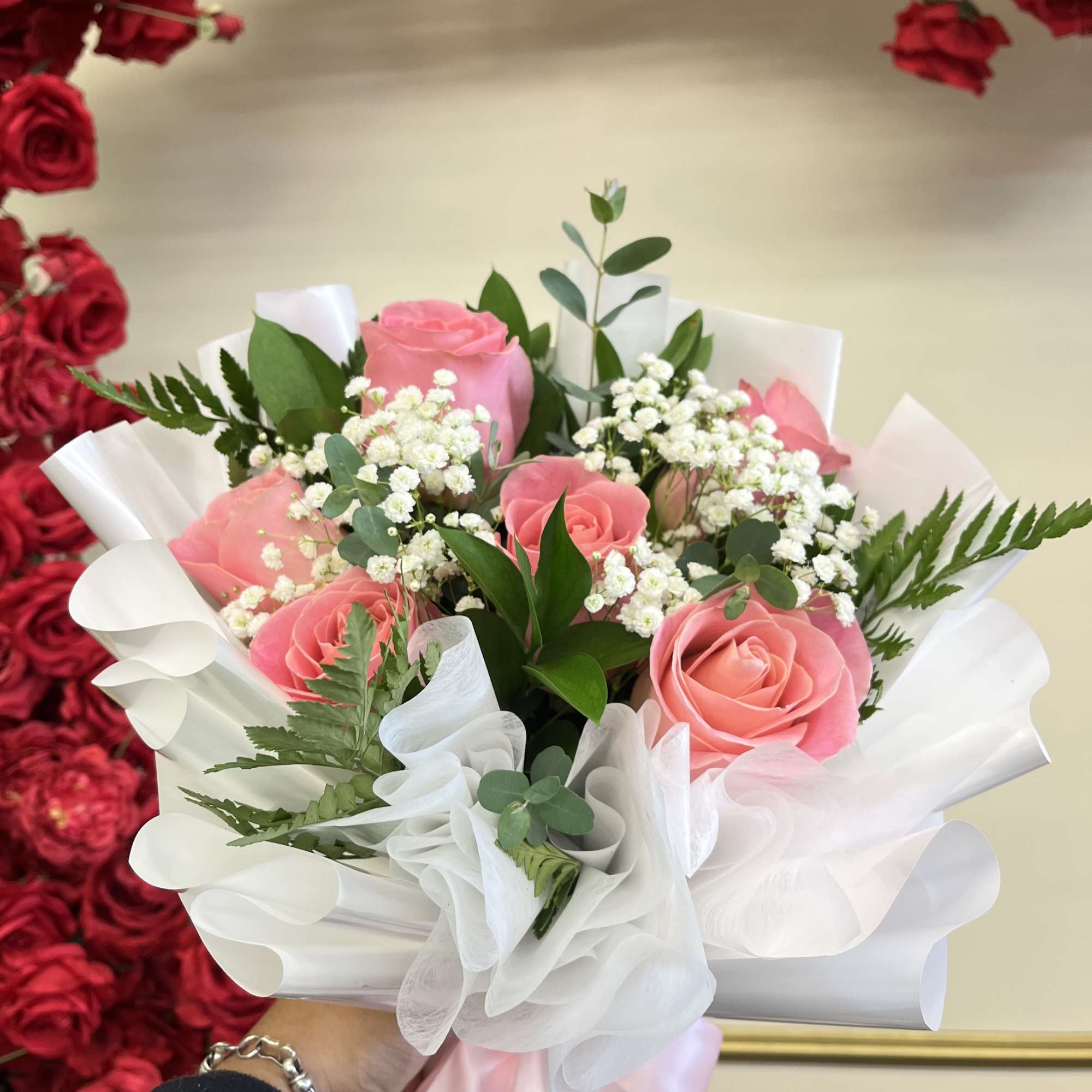 Pink roses in white wrapping with baby's breath and greenery