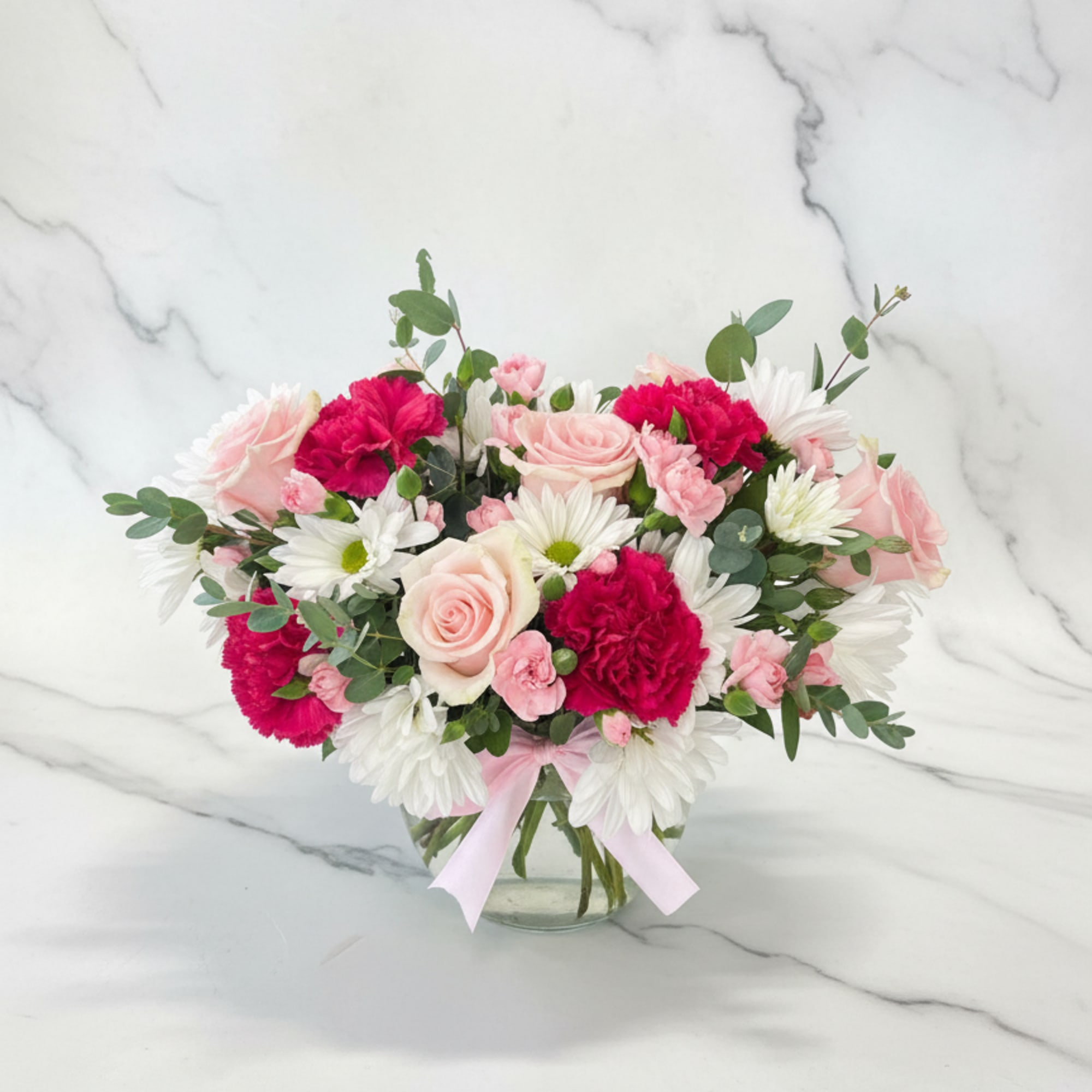 A low vase arrangement designed with flowers flowing outward for a soft