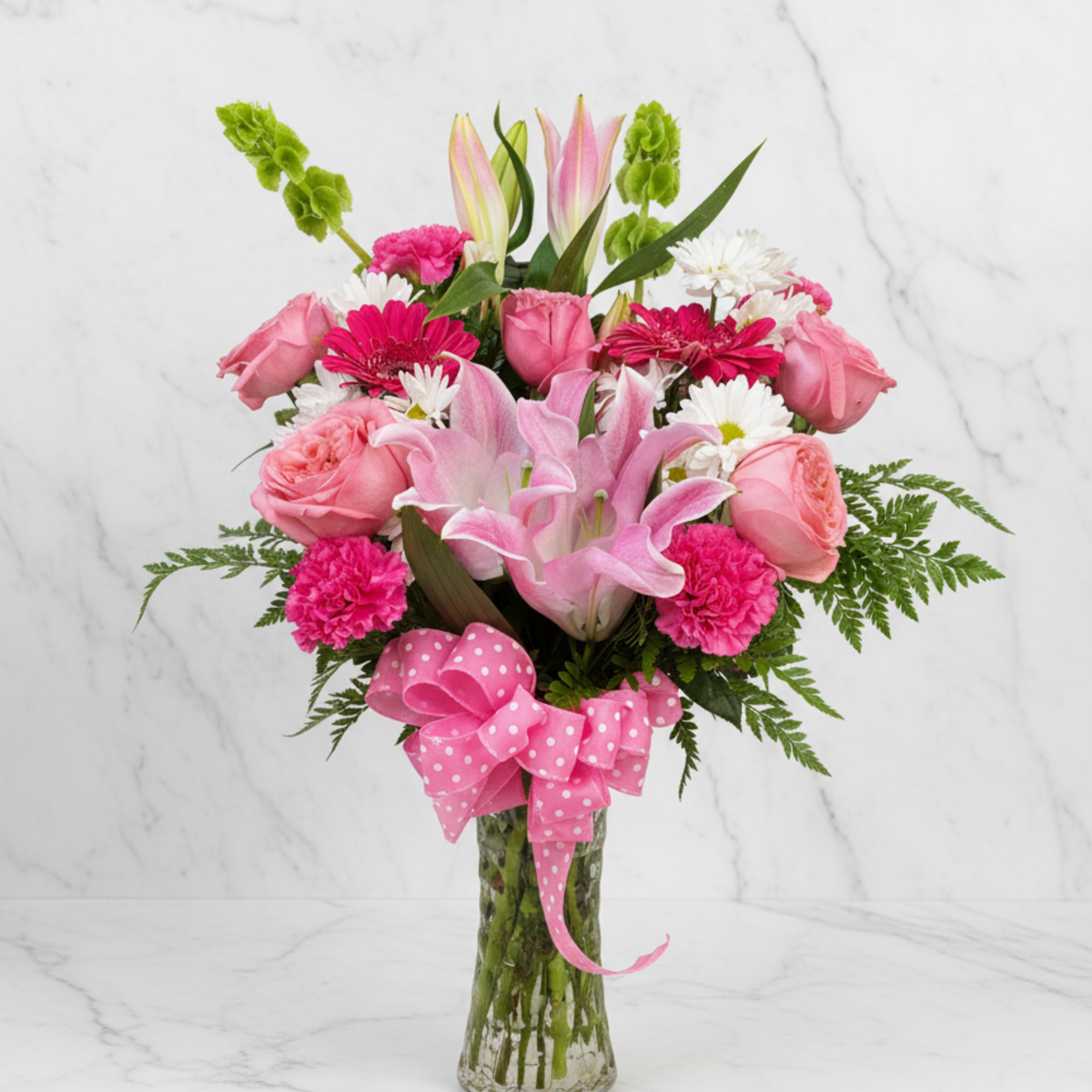 Pink lilies, roses, gerbera, carnations and white daisies in a clear vase